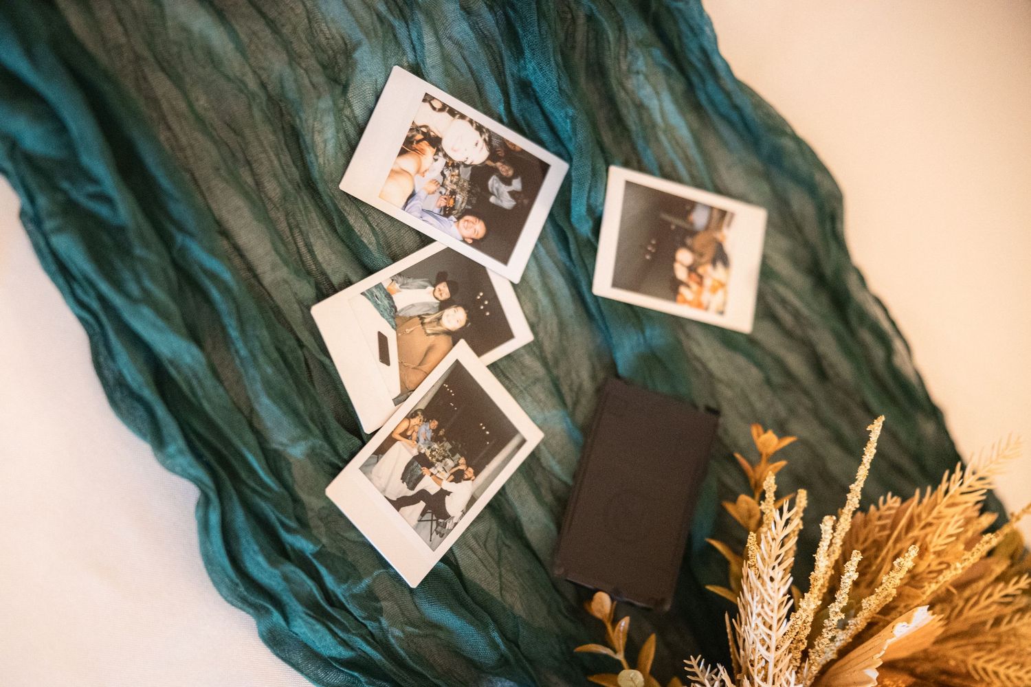 Vintage polaroid photos displayed on teal fabric with dried wheat accents.
