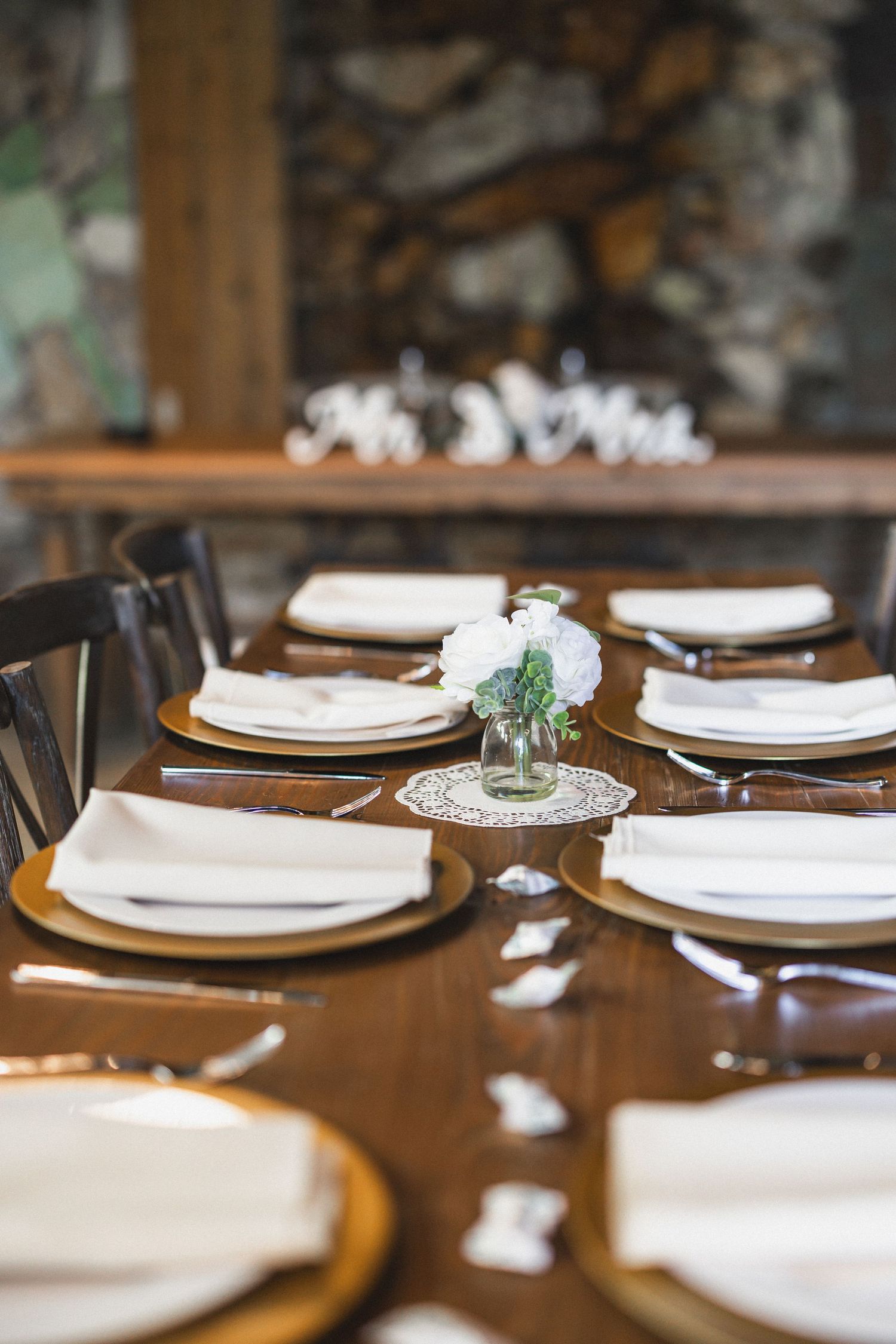 Elegant table setting with white plates, doilies and floral centerpieces.