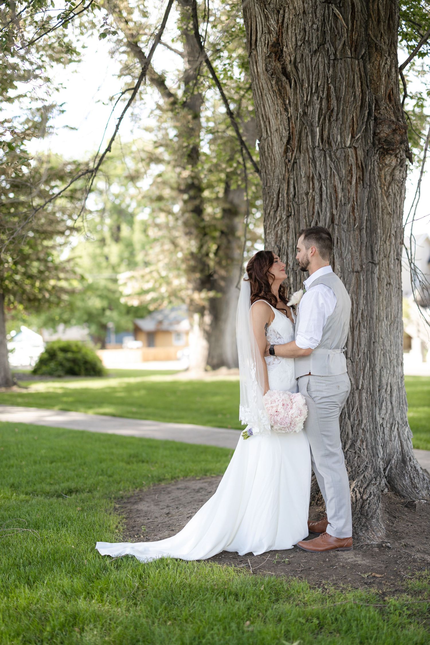 Romantic wedding portrait beneath large tree with soft natural lighting.