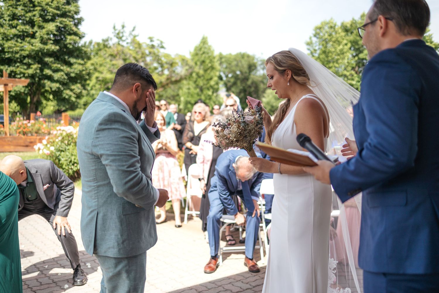 Guests celebrate at an outdoor wedding ceremony with white chairs and decorative gazebo.