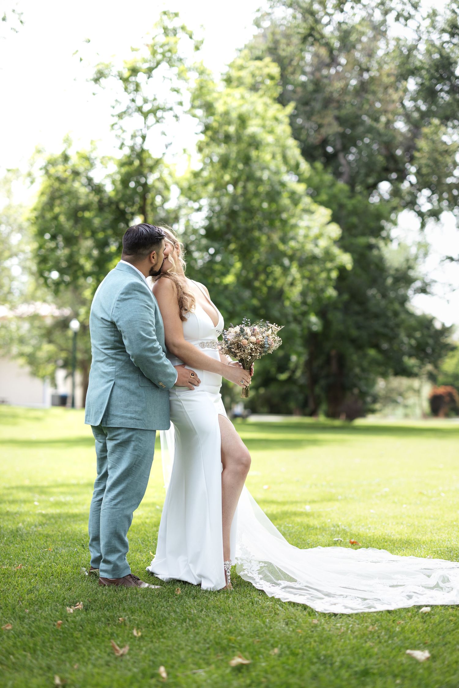 Bride and groom share romantic embrace during outdoor wedding photoshoot.