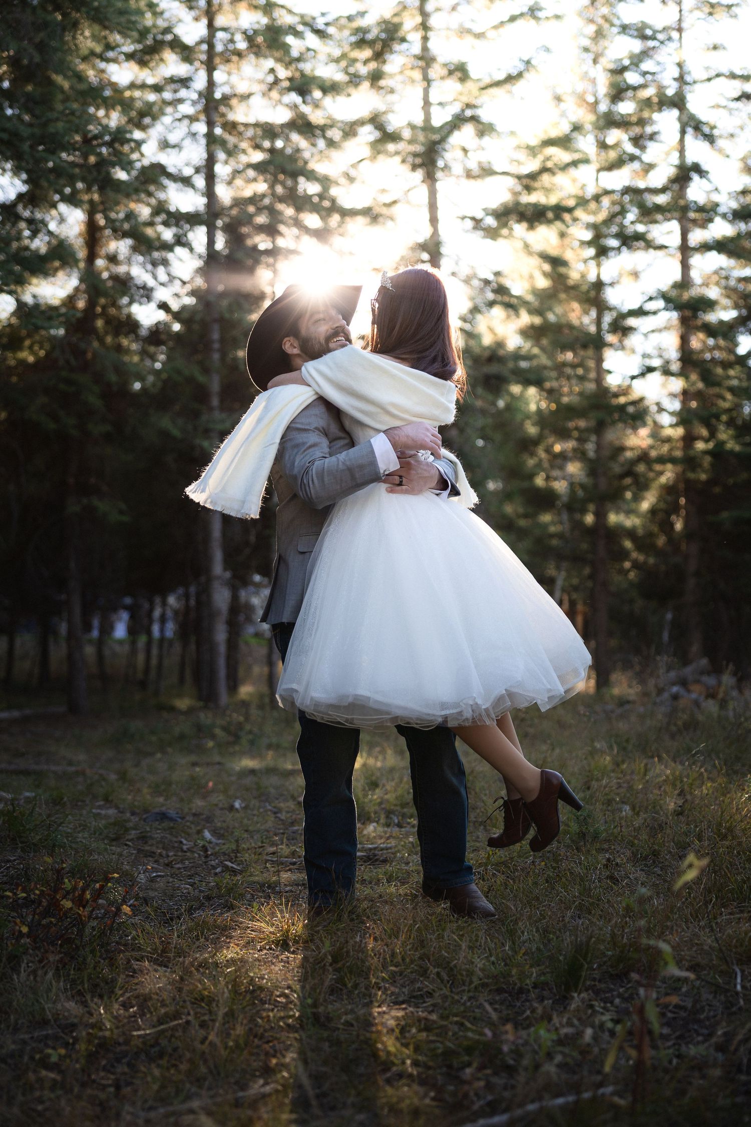 Wedding couple sharing an intimate lift pose together in a sun-drenched forest setting.