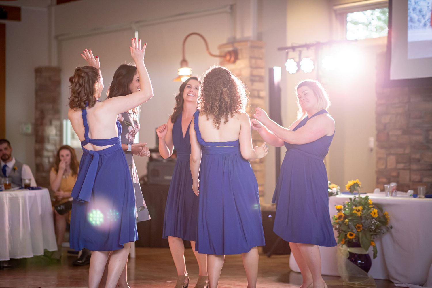 Bridesmaids in blue dresses dance together at a wedding reception.