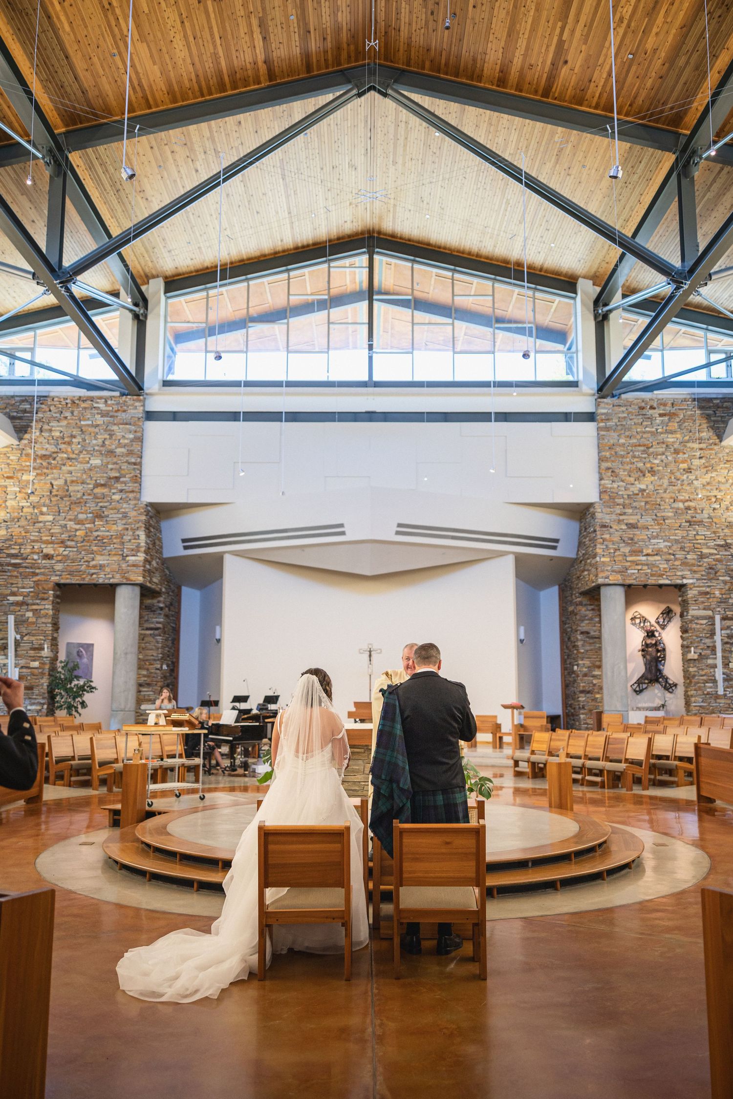 Modern church sanctuary with stone walls and wooden beams during wedding ceremony.