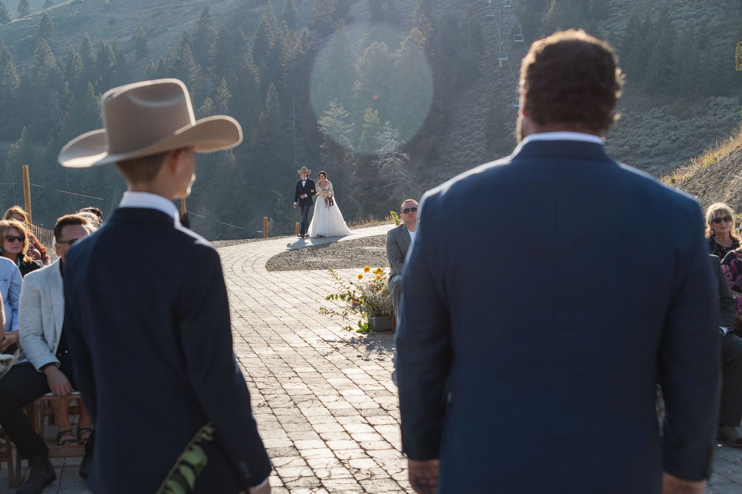 Wedding ceremony taking place on a mountain overlook with guests watching the couple against a scenic backdrop.