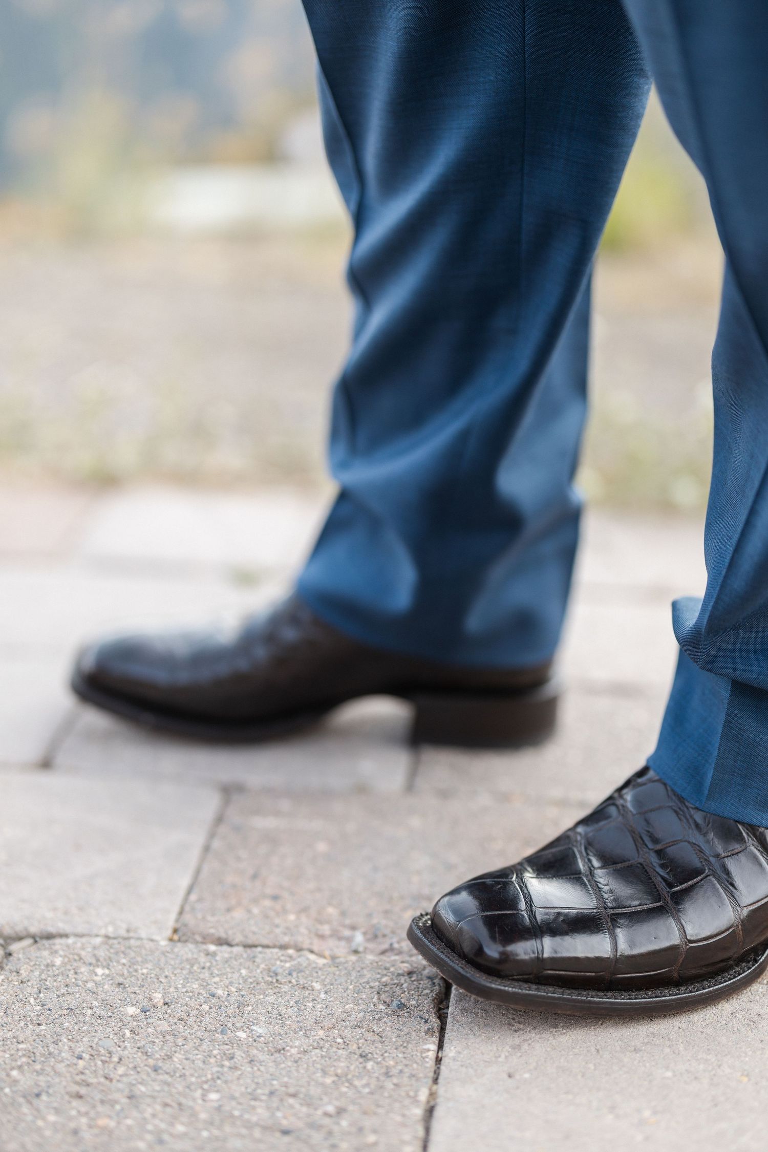 Close-up shots of black leather dress shoes on concrete ground.