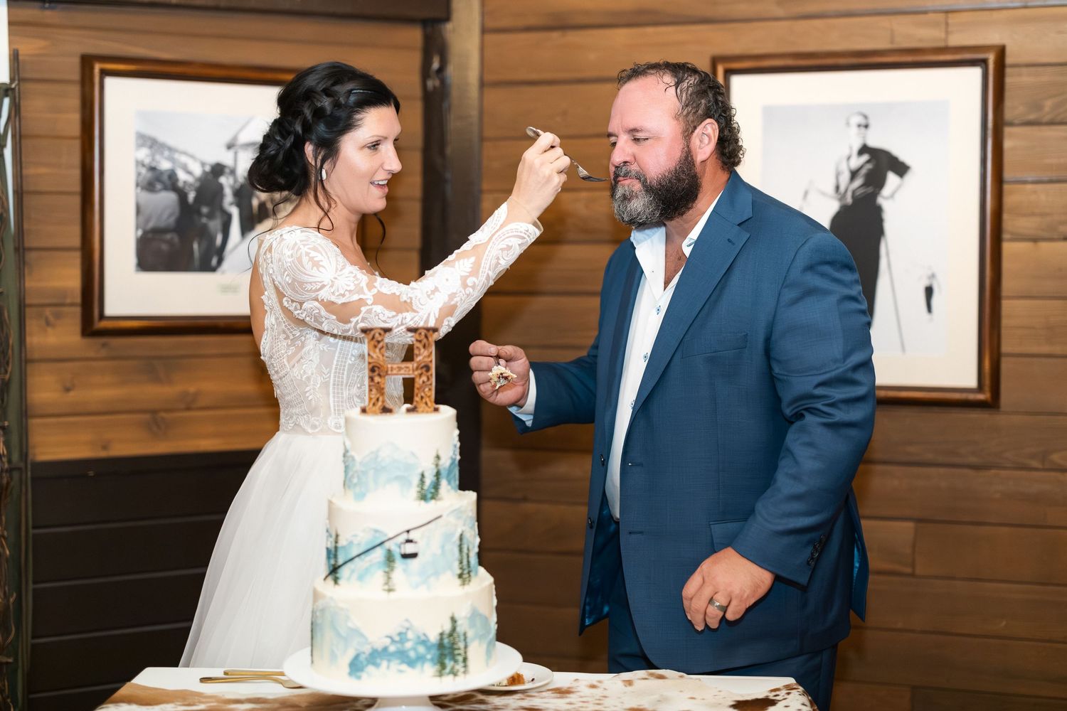 Newlyweds playfully feed each other wedding cake during their reception.