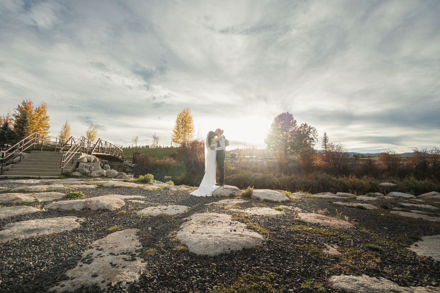 Silhouette of wedding couple against sunset with dramatic cloudy sky.