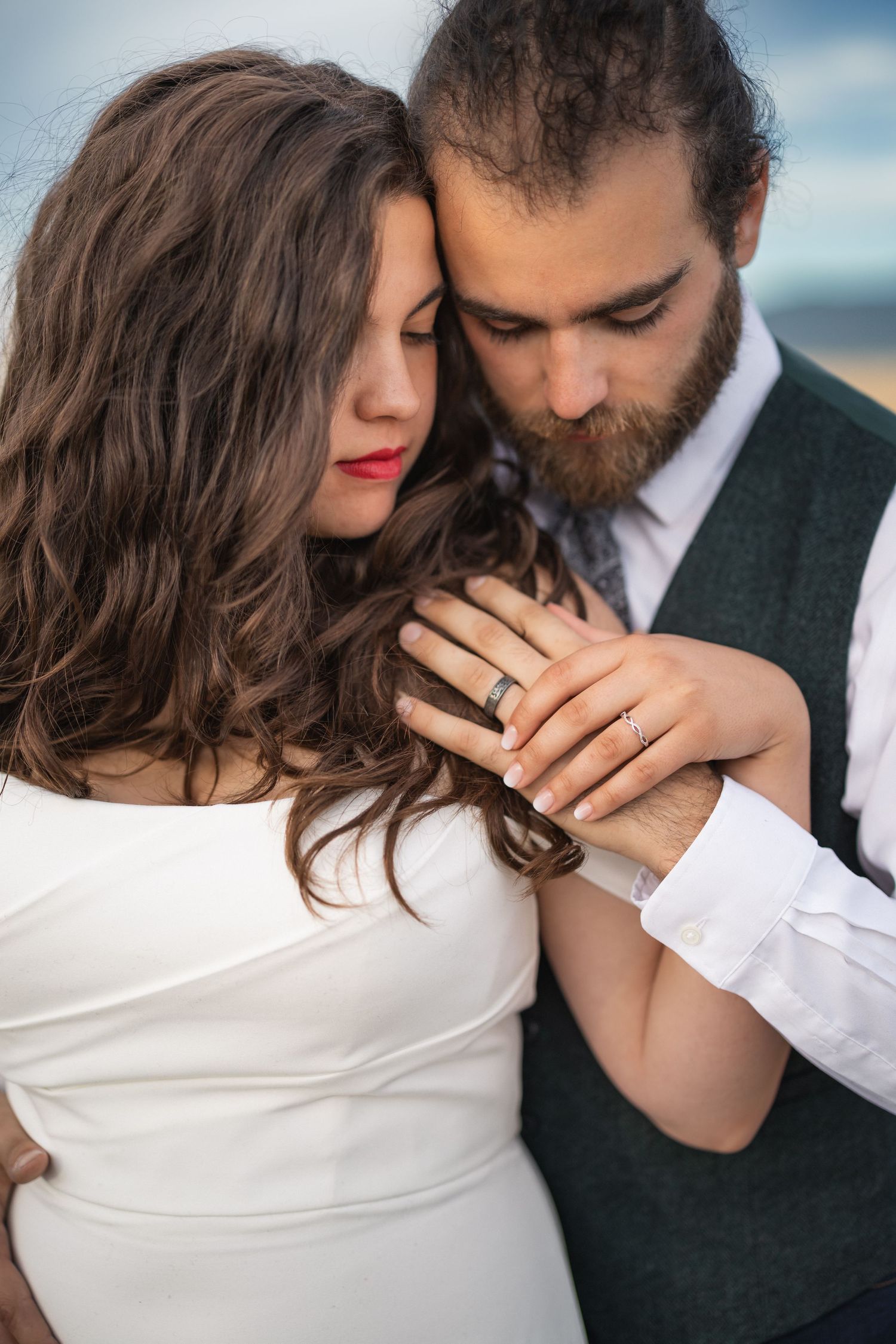 Intimate moment captured showing wedding rings and formal attire against natural backdrop.
