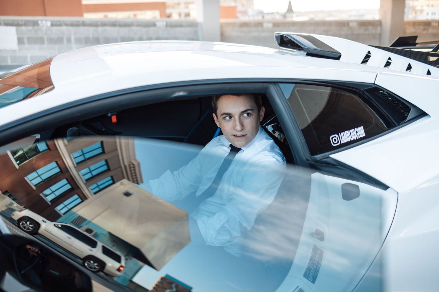 View through car window of person sitting in white Lamborghini supercar.