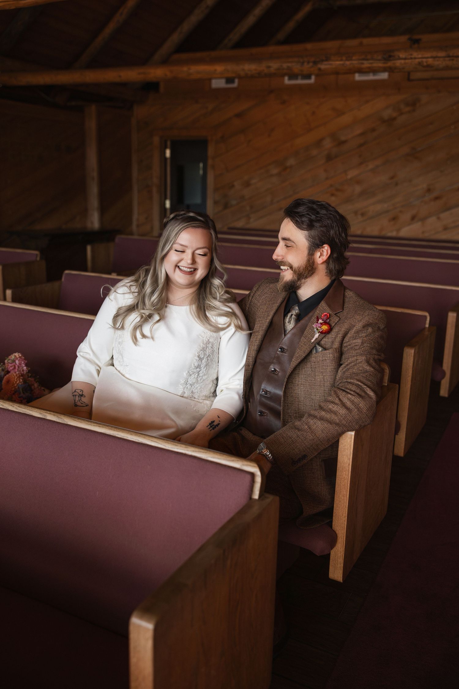 Couple sharing intimate moment while sitting in vintage wooden church pews.