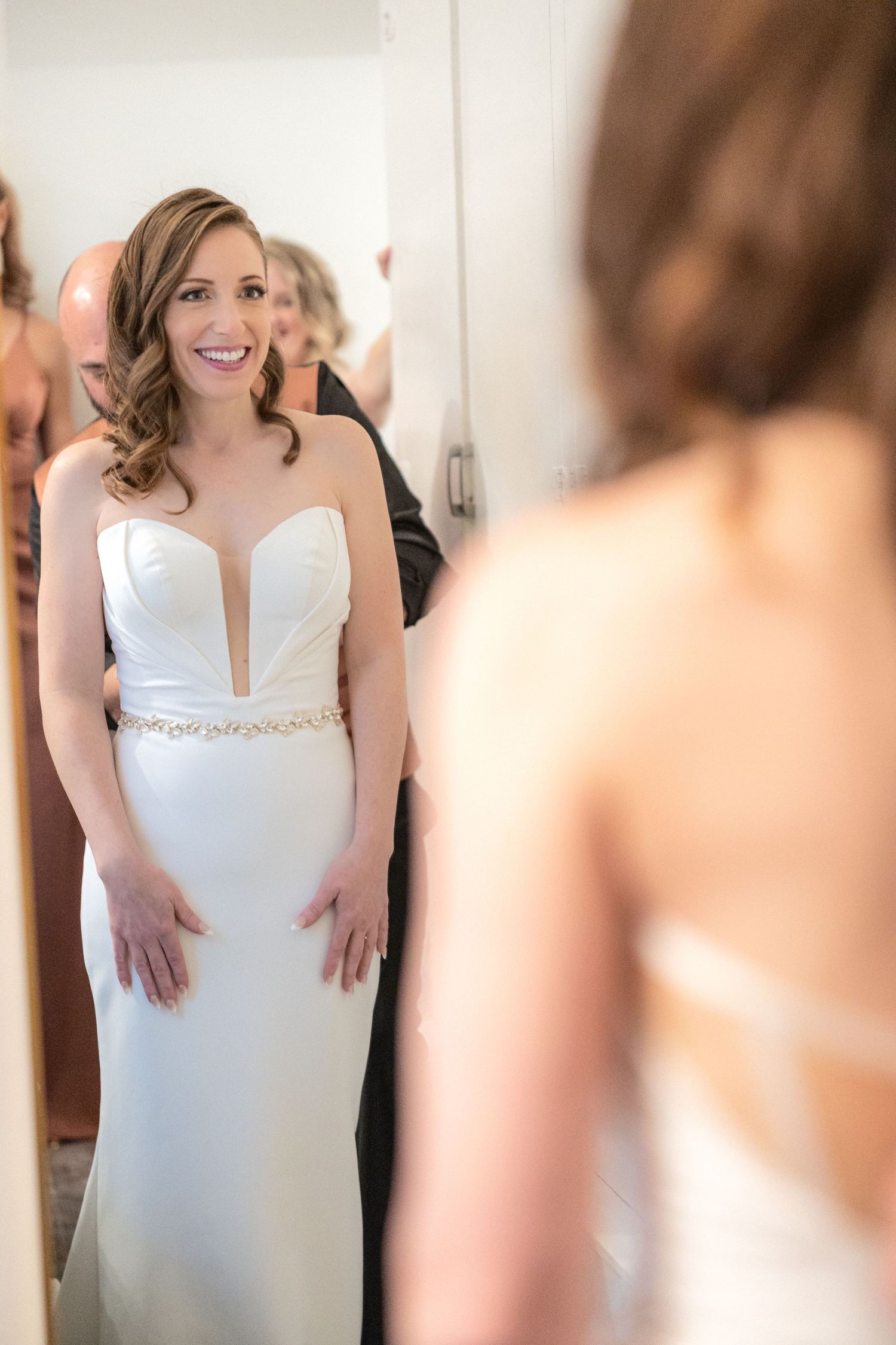 Wedding dress fitting moment captured in a mirror reflection.
