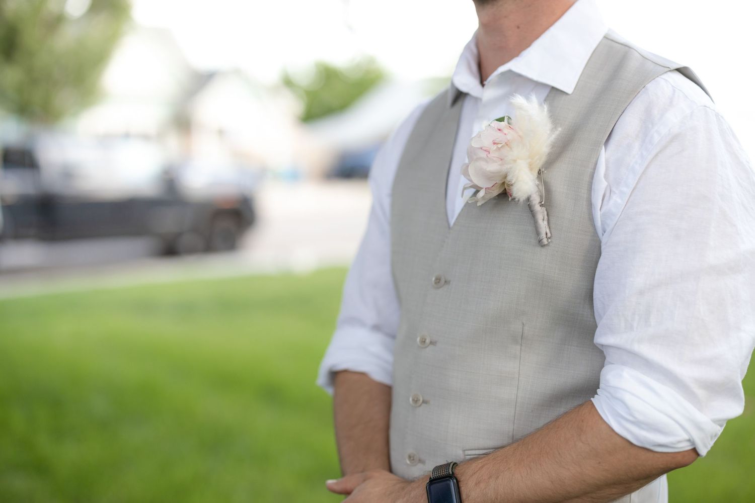 Close up of groom's light gray vest with white boutonniere.