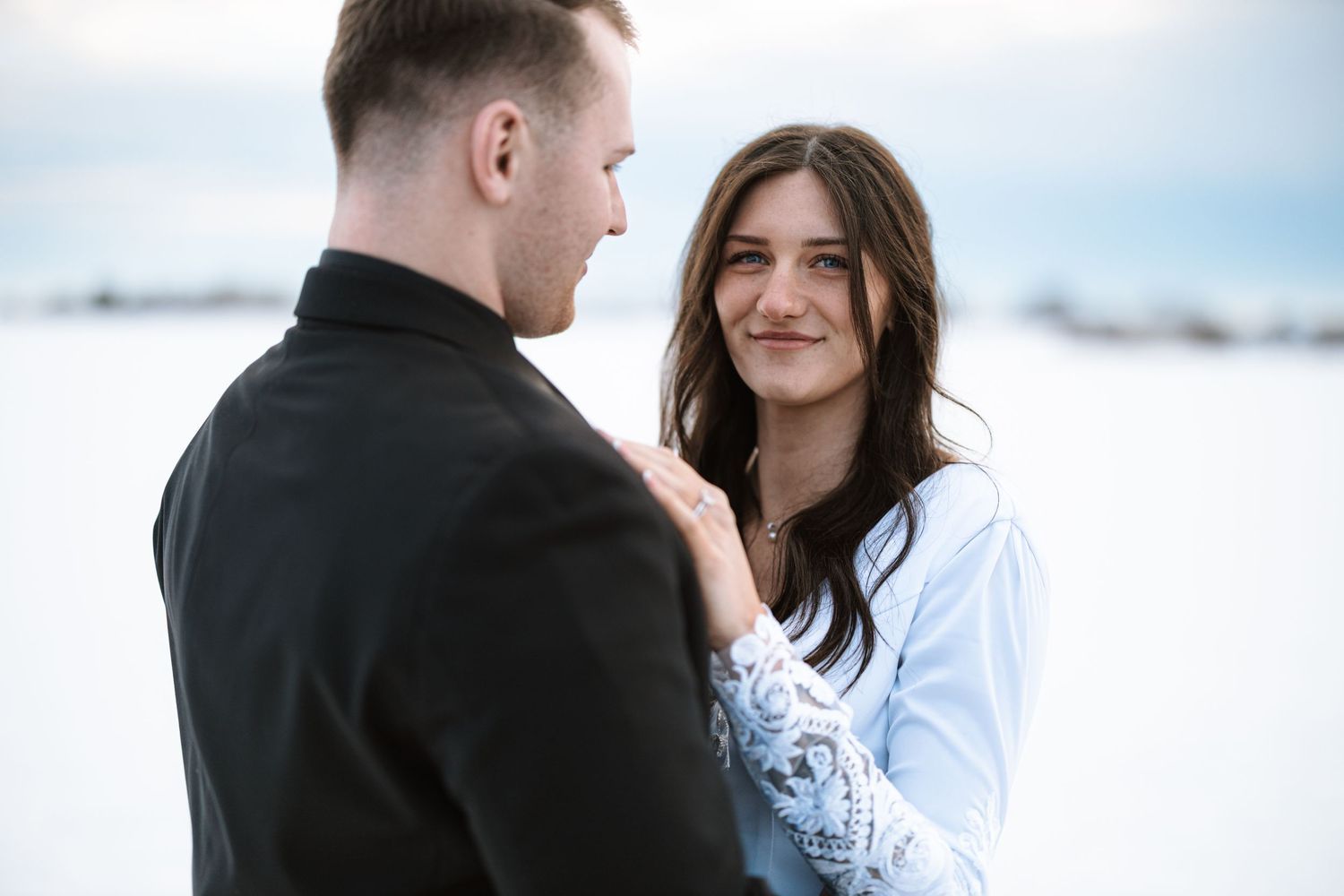 Intimate winter wedding portrait with snowy landscape backdrop.