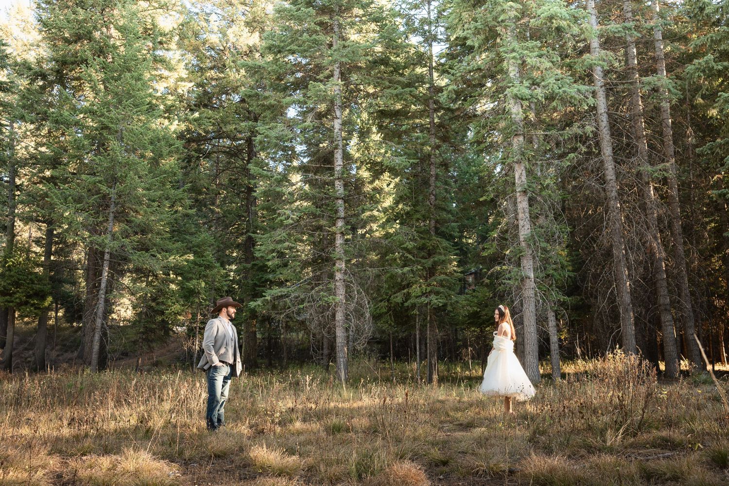 A wedding photoshoot in a forest clearing with tall pine trees in the background.
