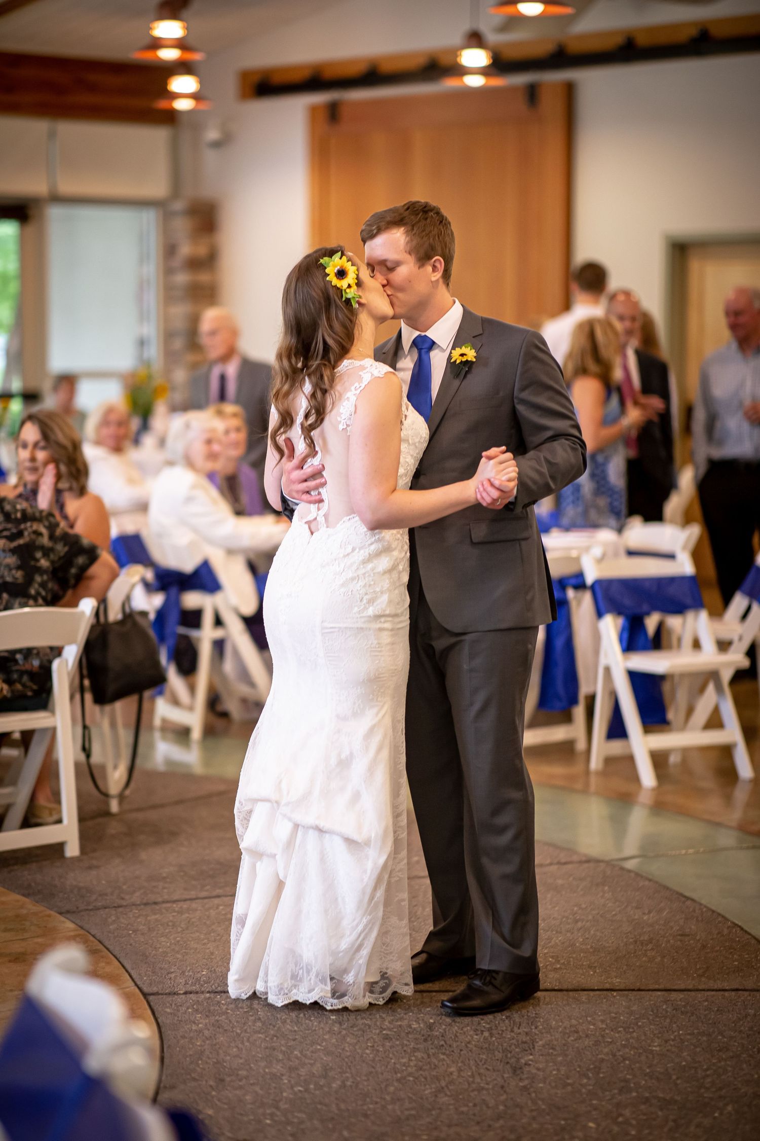 A couple shares their first dance at a wedding reception with blue decor.