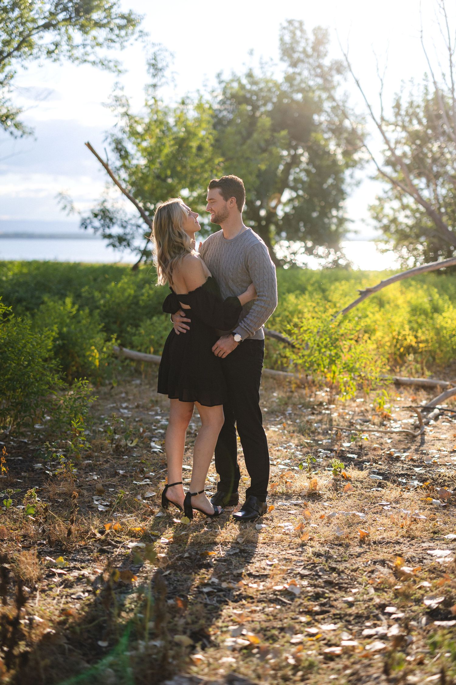 Romantic outdoor portrait of couple embracing on sunlit path.