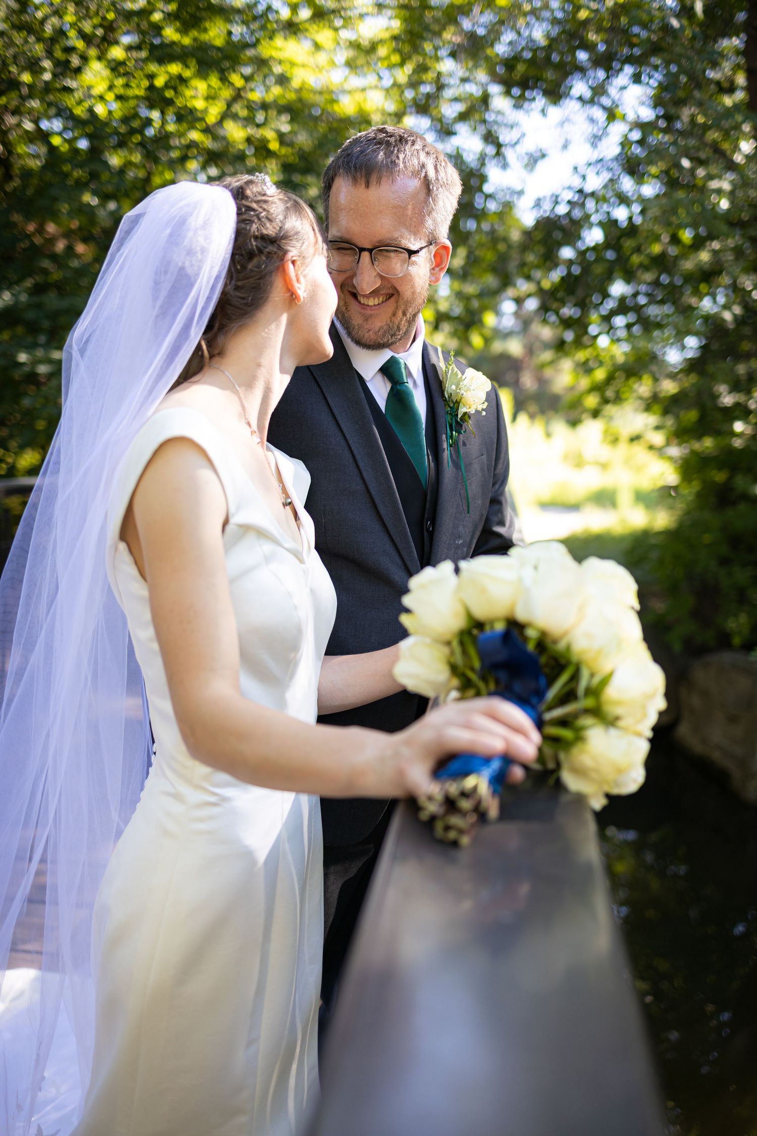 A couple shares a tender moment while holding a bouquet of white flowers.
