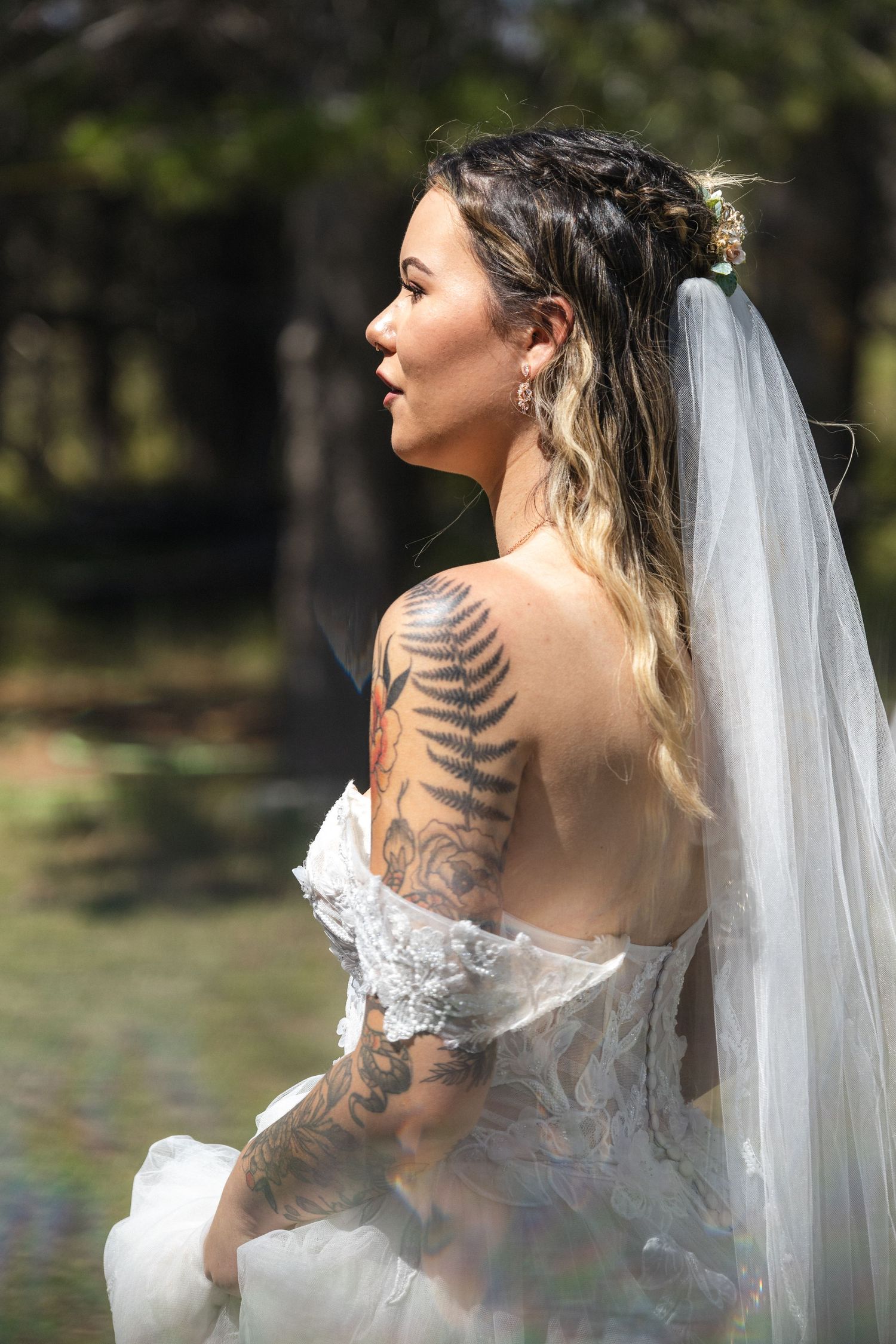 A detailed side view of a bride's intricate lace dress and fern tattoo design.