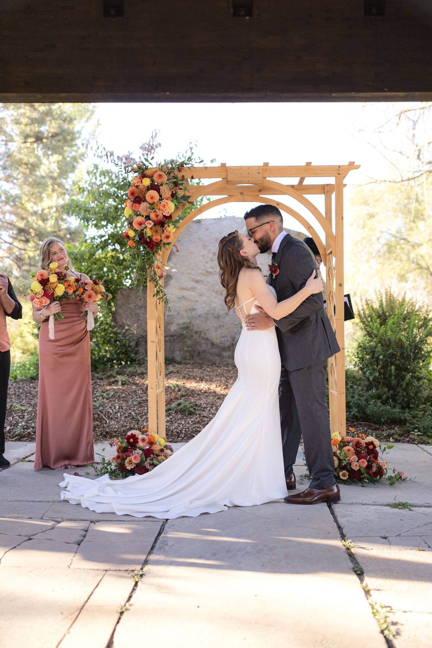 Wedding ceremony sequence showing couple at wooden arch with coral floral decorations.
