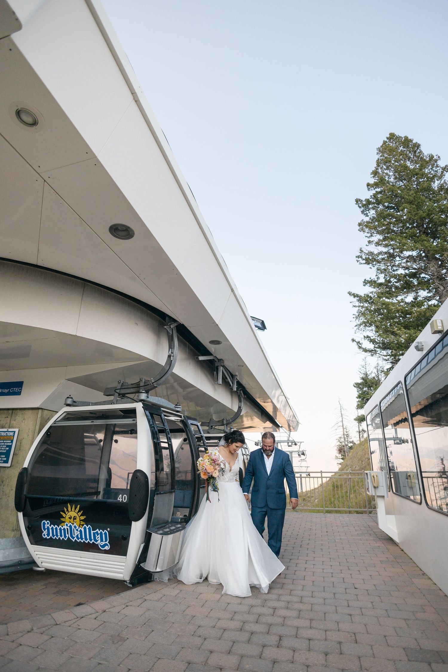 Panoramic view of a ski resort gondola station with wedding couple posing outside.