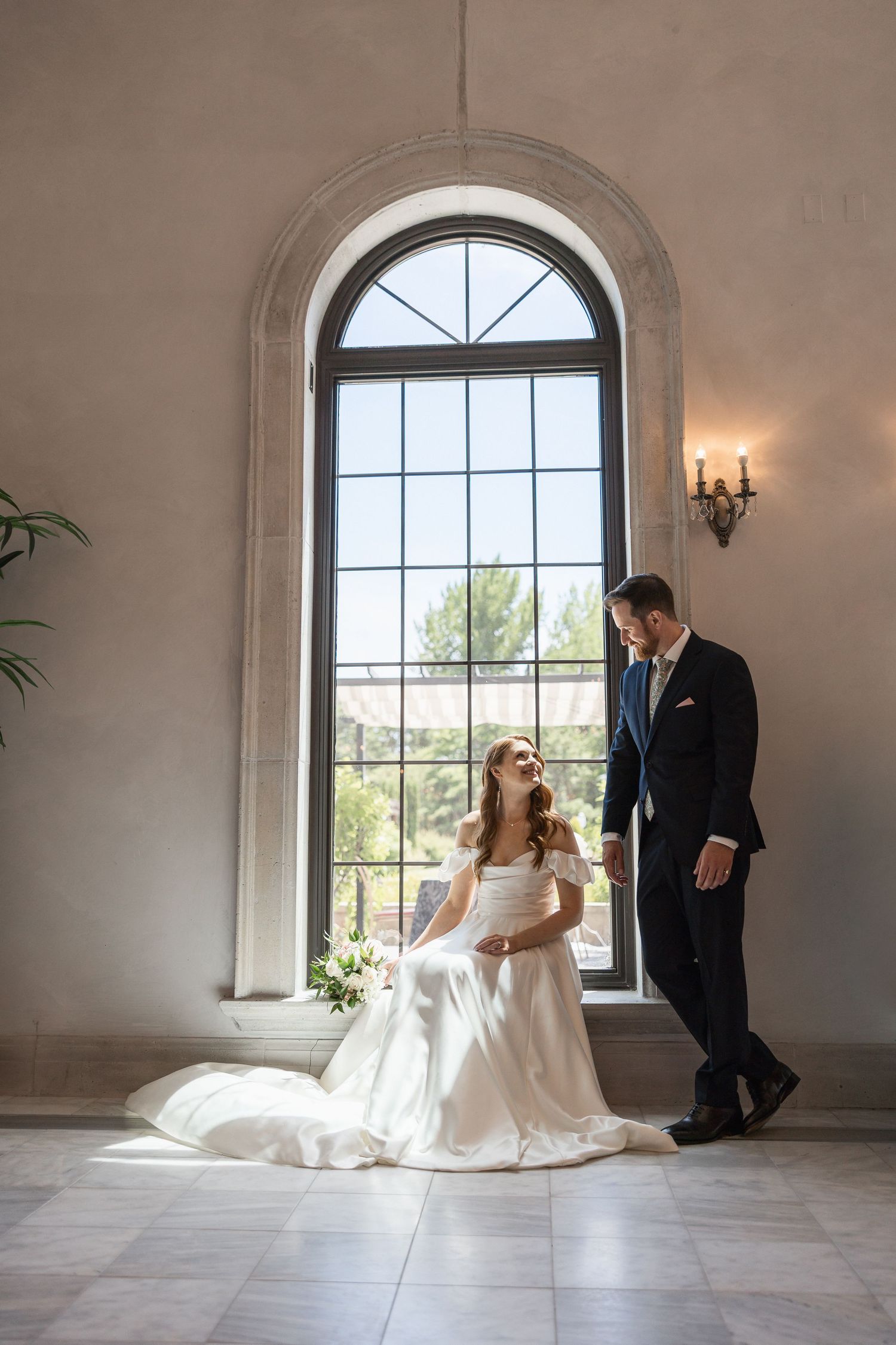 Elegant wedding moment by arched window with natural light streaming in.
