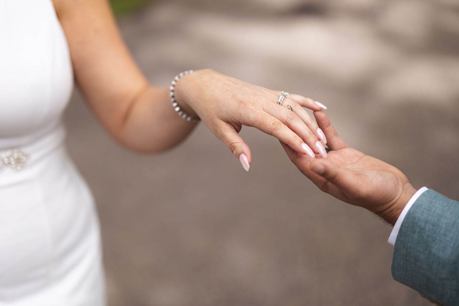 Close-up shot of hands with wedding rings during ceremony outdoors.