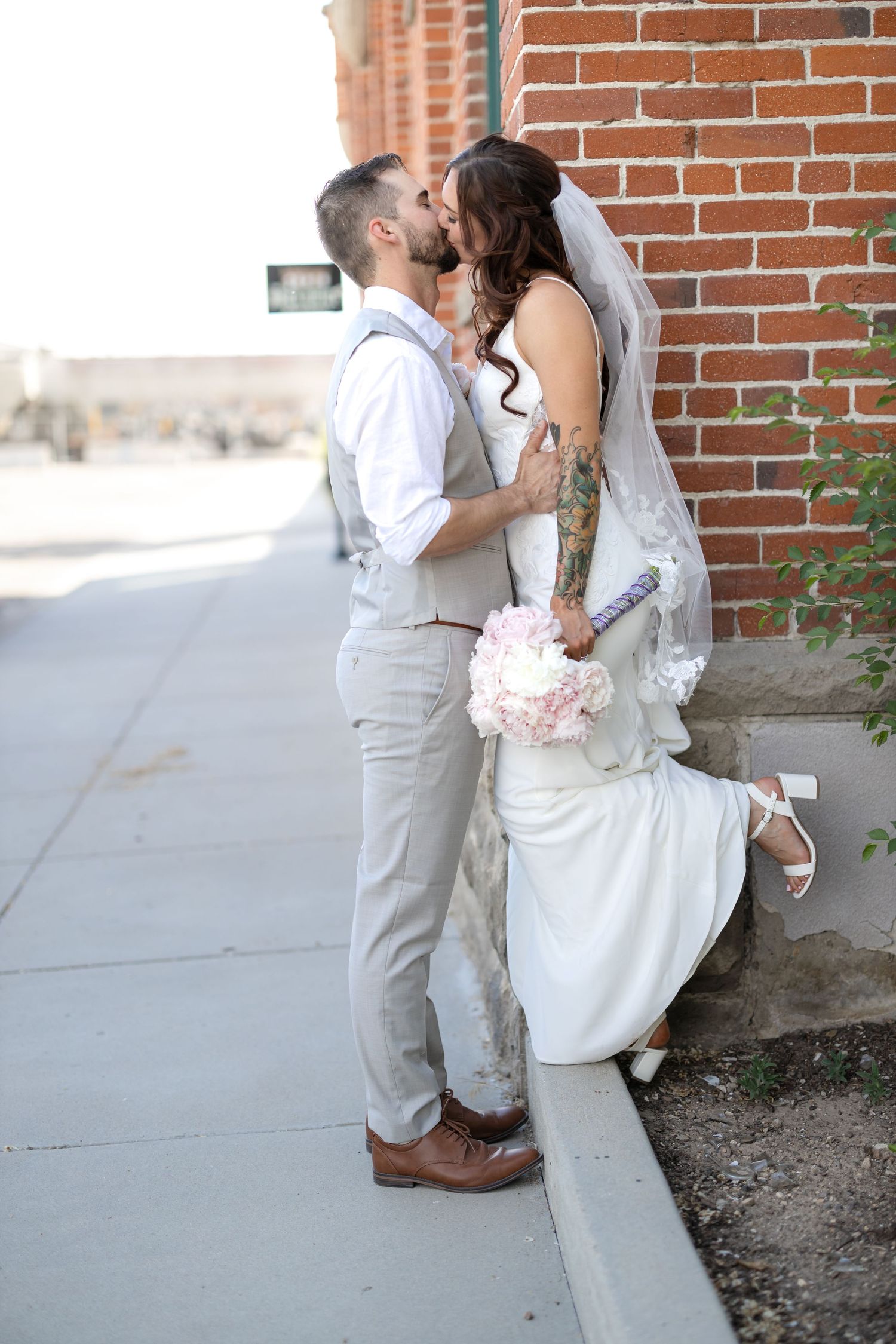 Intimate wedding moment captured against rustic brick wall backdrop.