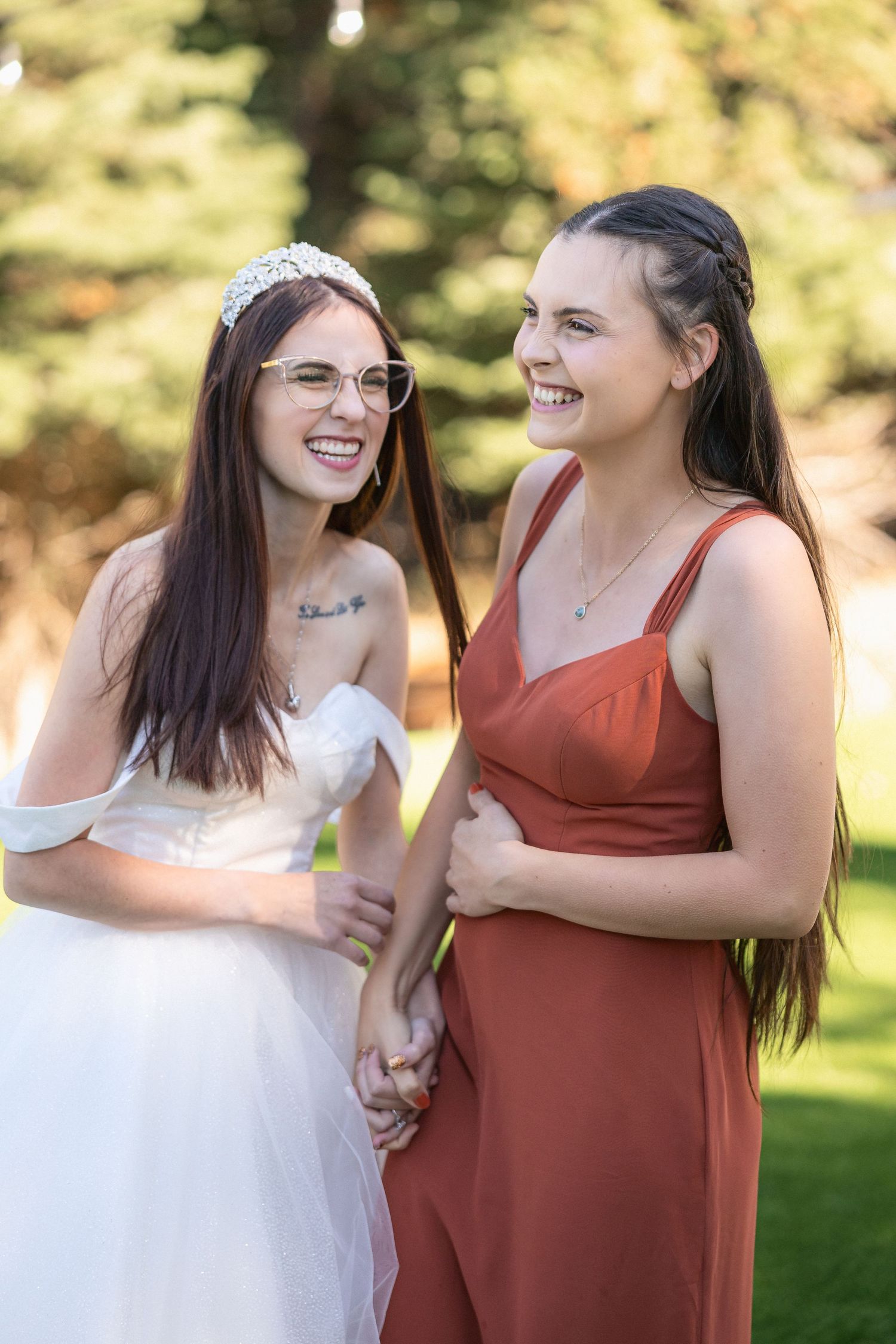 Wedding party members share joyful moment in outdoor garden setting.