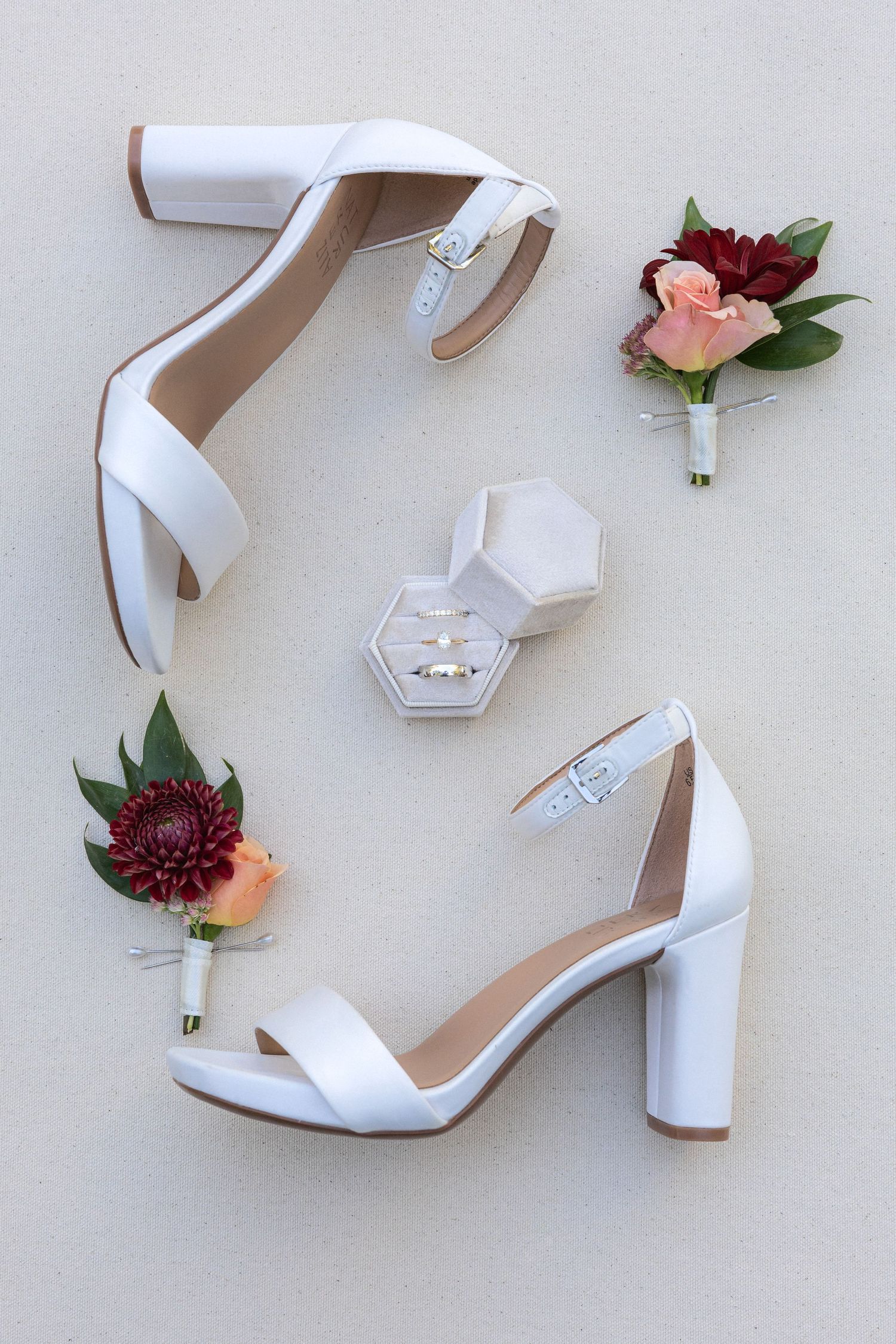 White wedding heels with block heel and floral boutonnières featuring deep burgundy dahlias and peach roses.