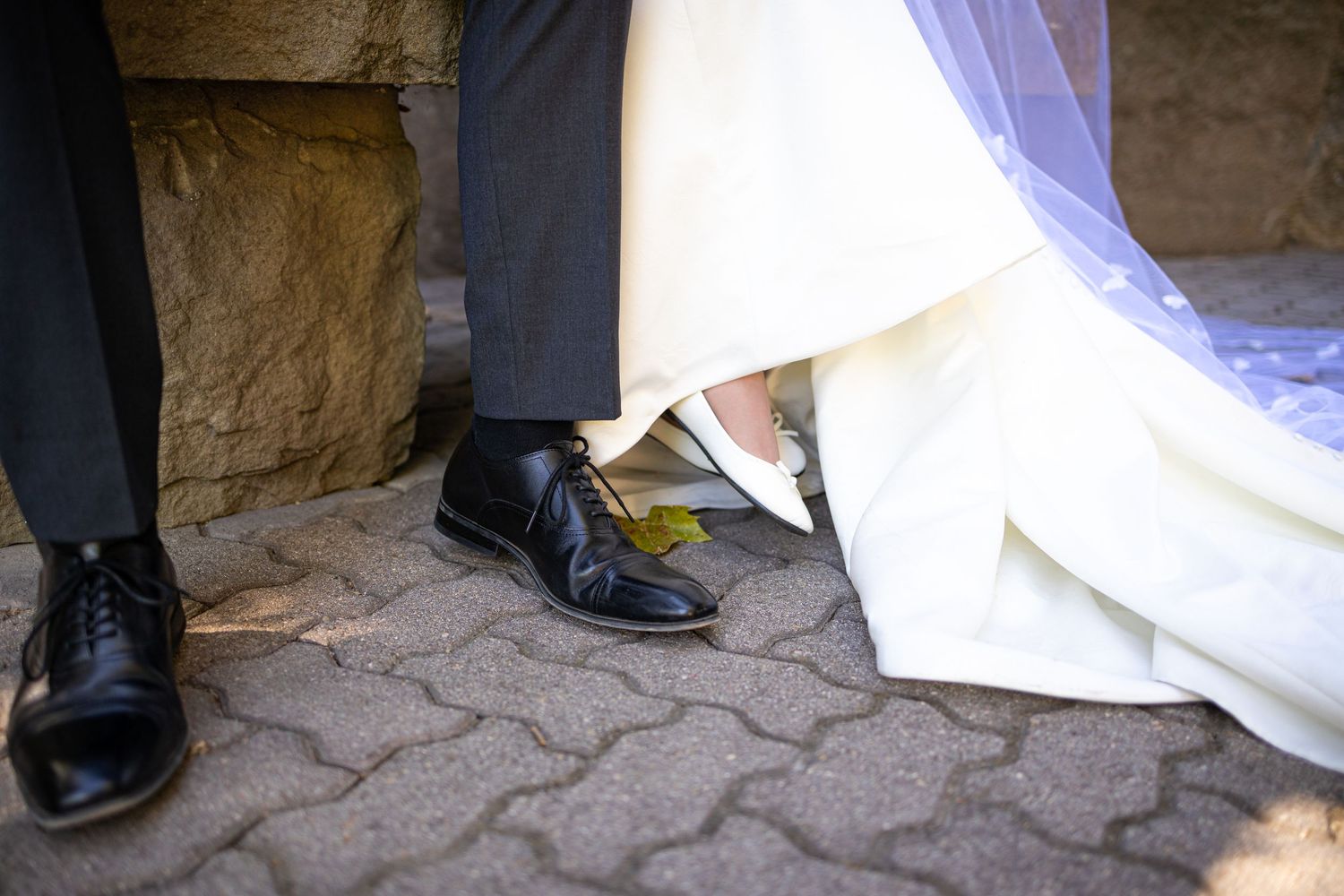 Detail shot of bride and groom's shoes on patterned stone paving.