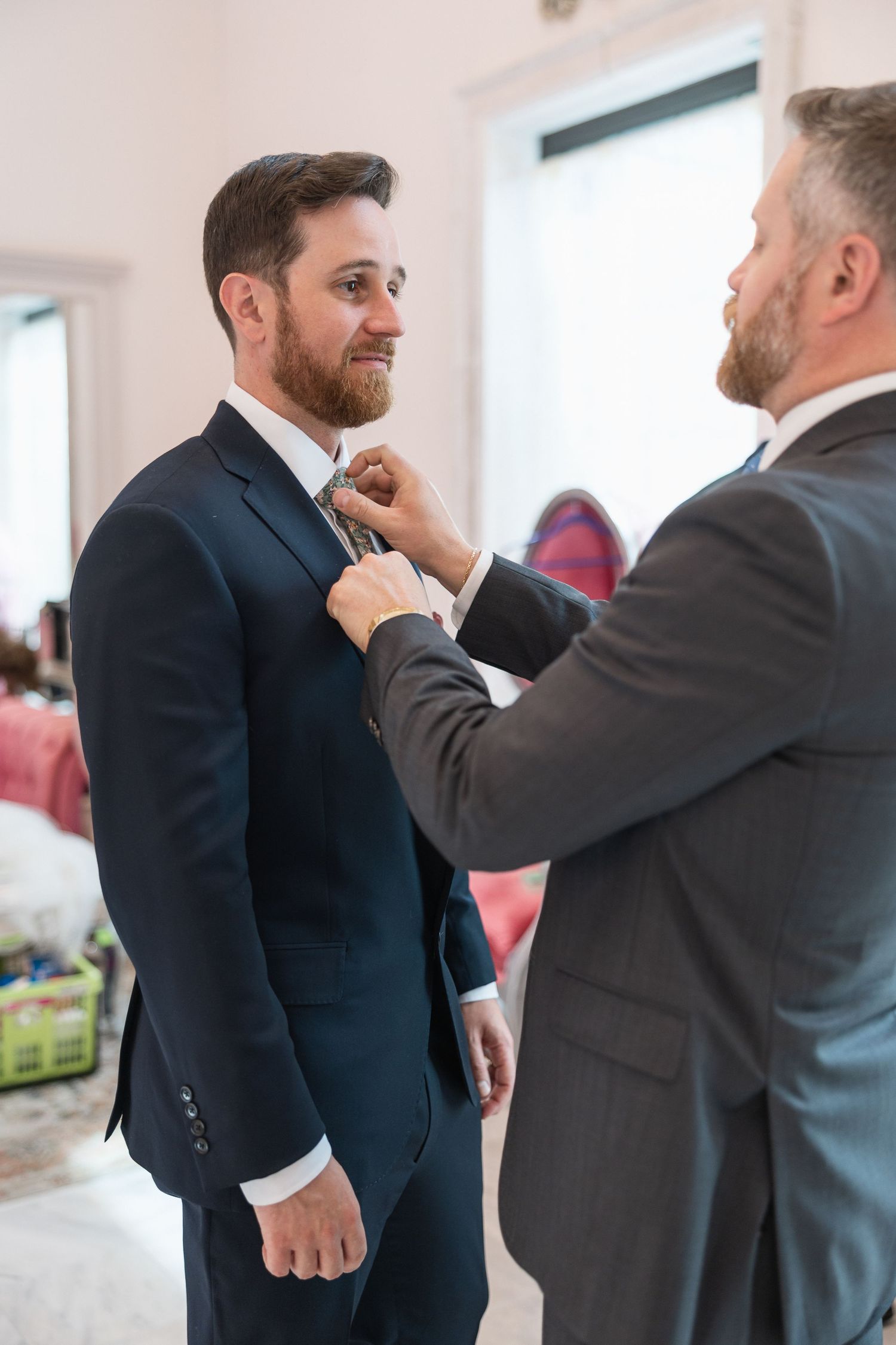 Men adjusting formal attire and ties before wedding ceremony.