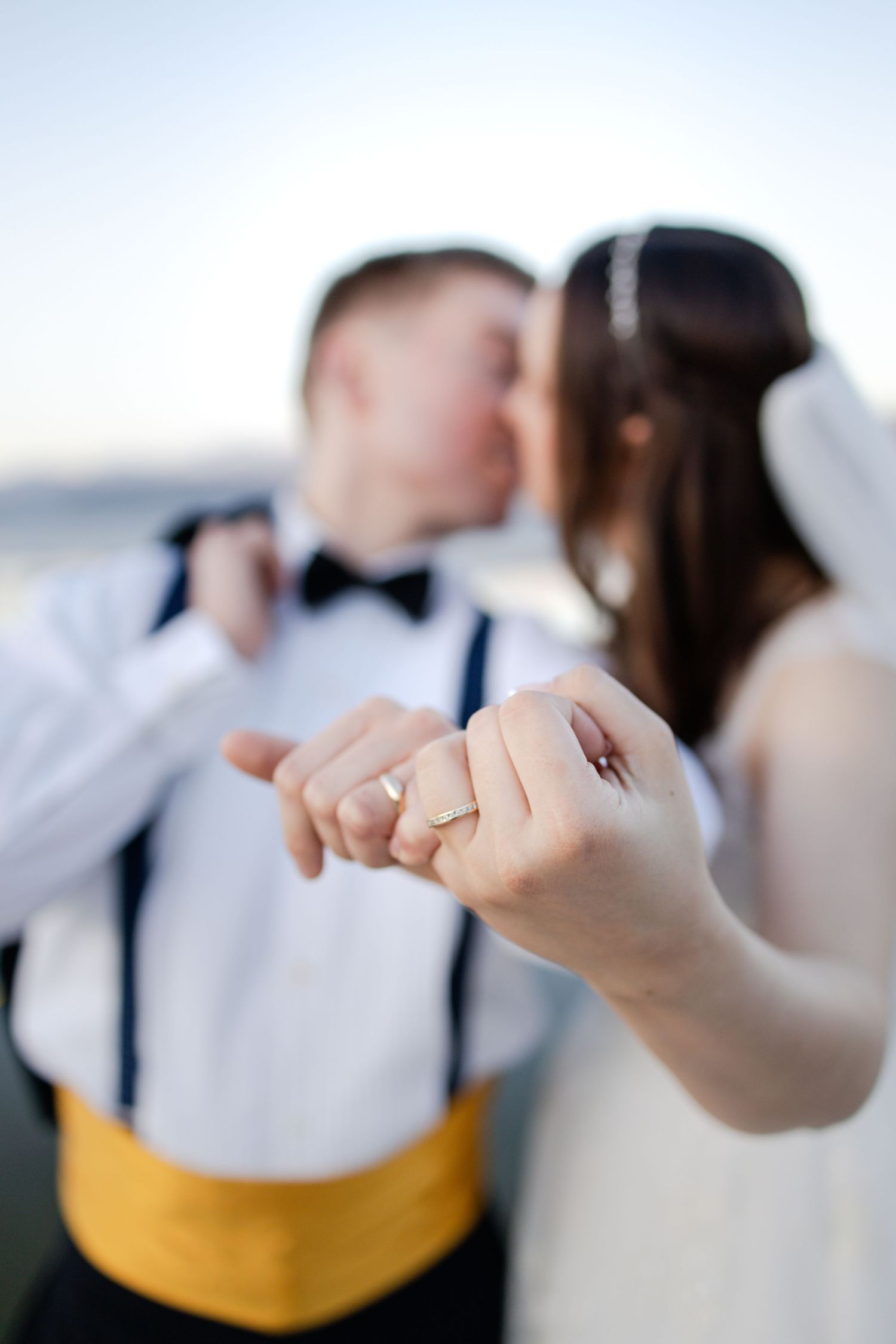 Close up of wedding rings and joined hands against a soft blurred background.