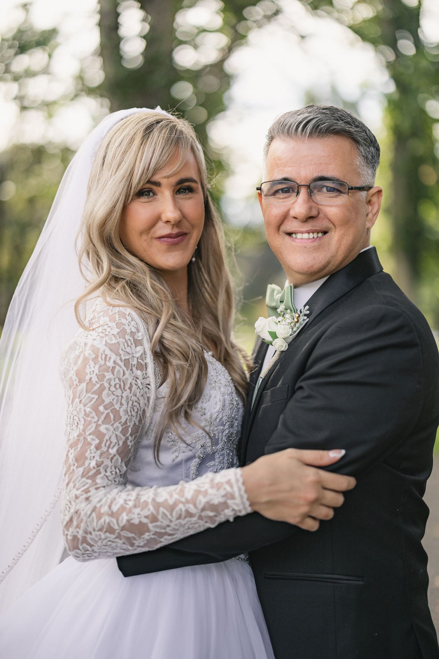 Wedding portrait in a lush green park setting on a sunny day.