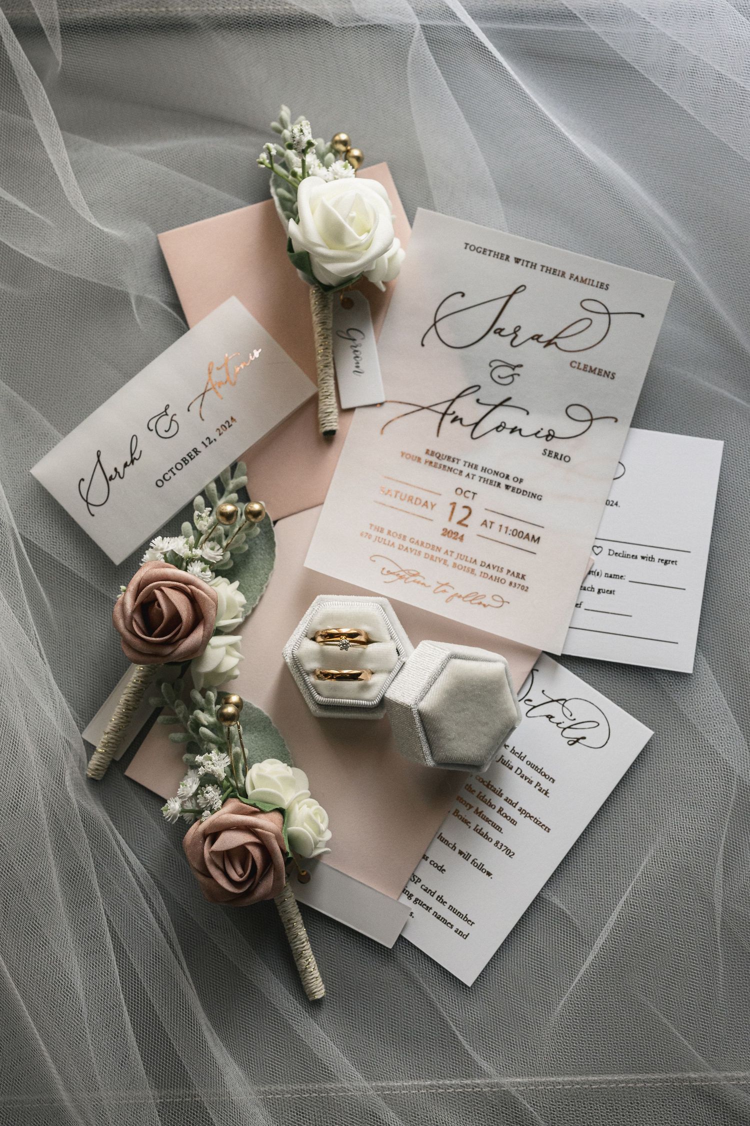 Wedding stationery suite with floral boutonnieres and ring box on tulle fabric.