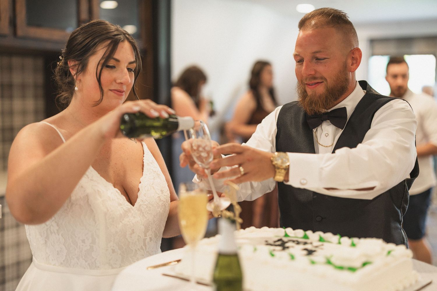 Celebratory moment at wedding reception as couple prepares to pour champagne.