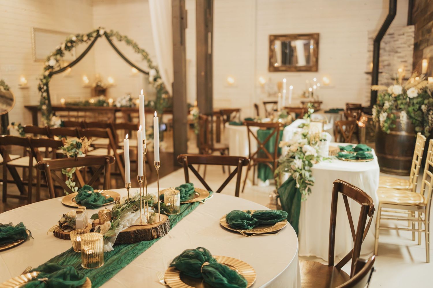 Elegant wedding reception table with emerald green and gold decor.