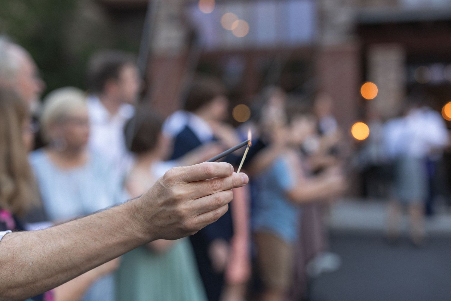 Close-up of a hand holding a phone during an outdoor evening wedding celebration.