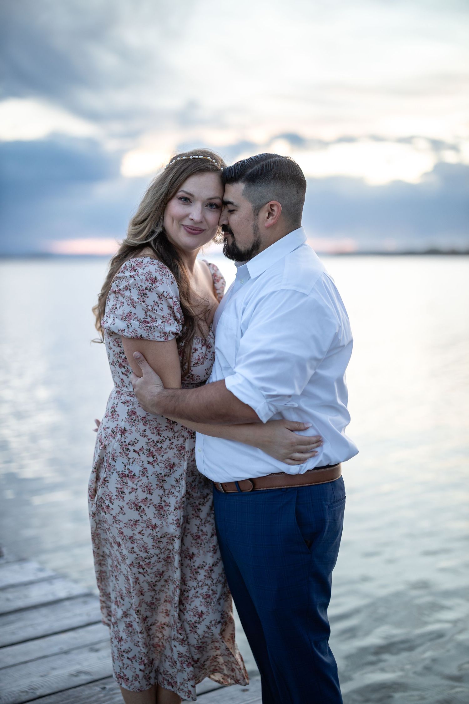Tender embrace shared on a wooden dock at sunset.