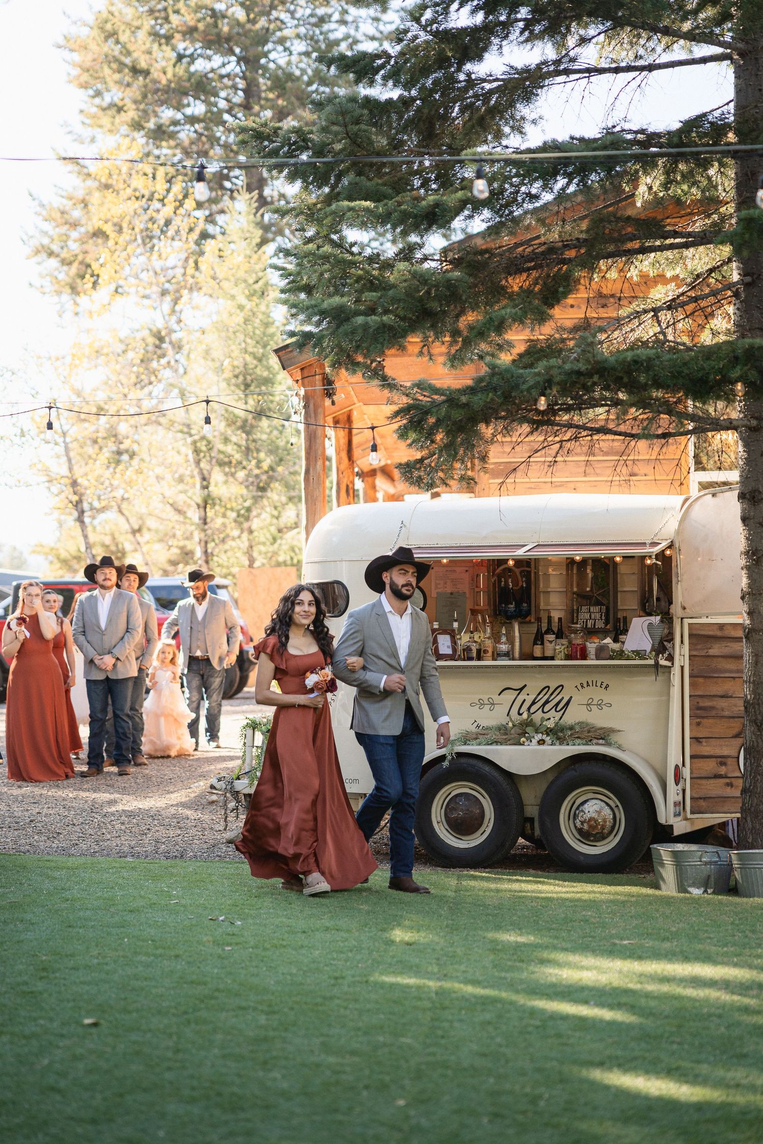 Outdoor wedding reception with a vintage food cart and guests in formal attire.