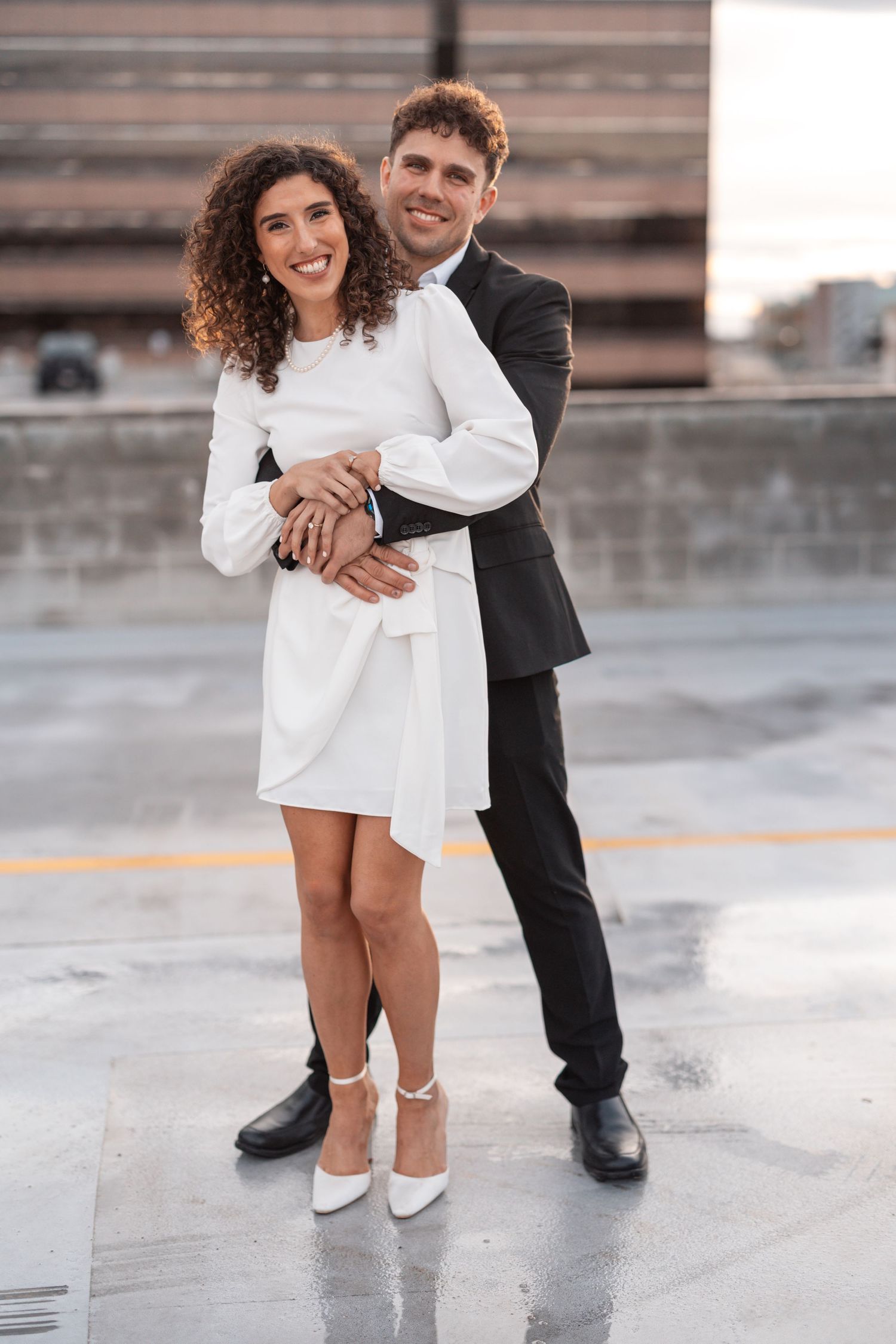 Couple dancing together on a rooftop parking structure shows detail of their contrasting black and white outfits.