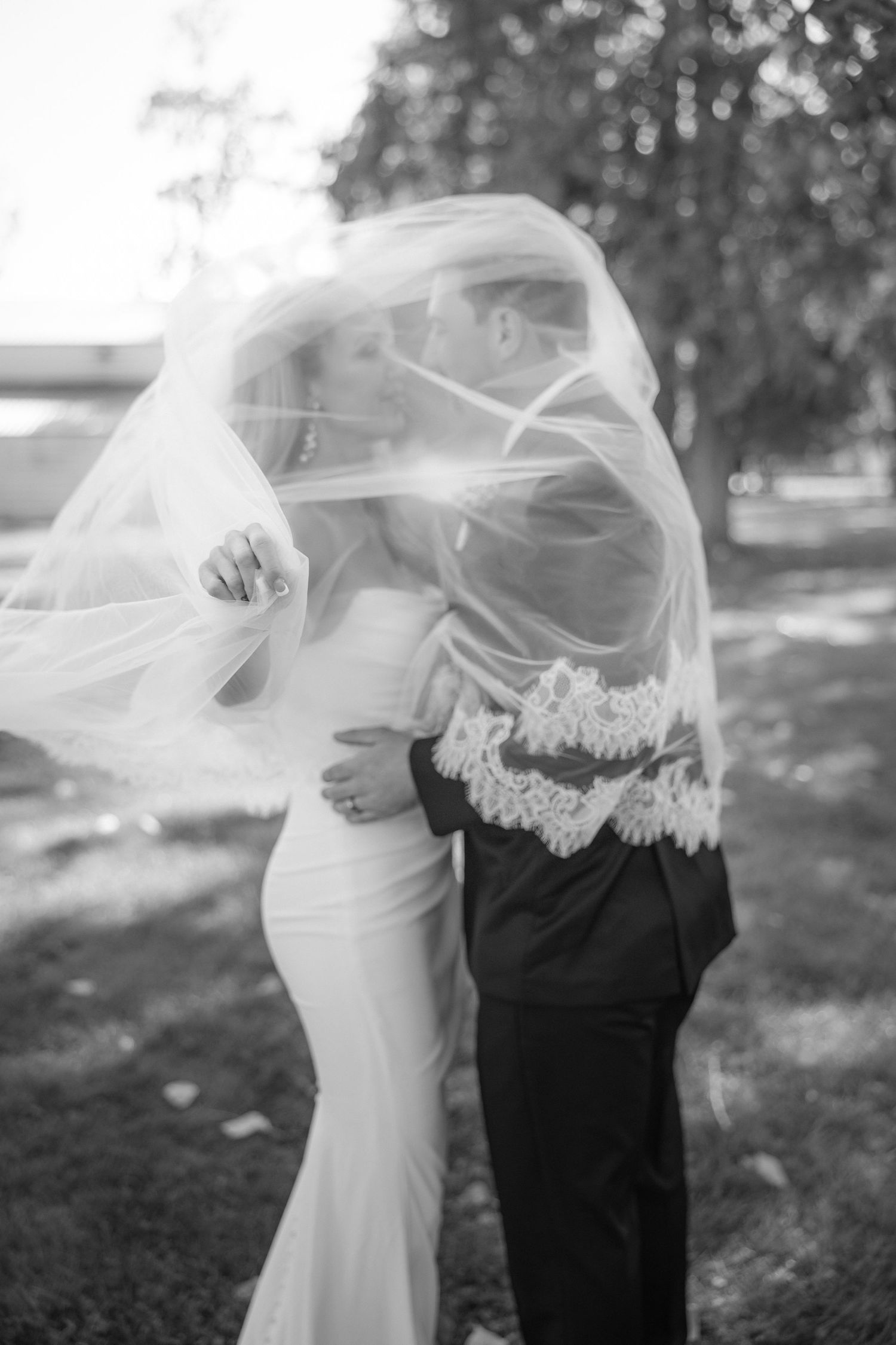 Black and white wedding portraits showing romantic veil moments in an outdoor setting.