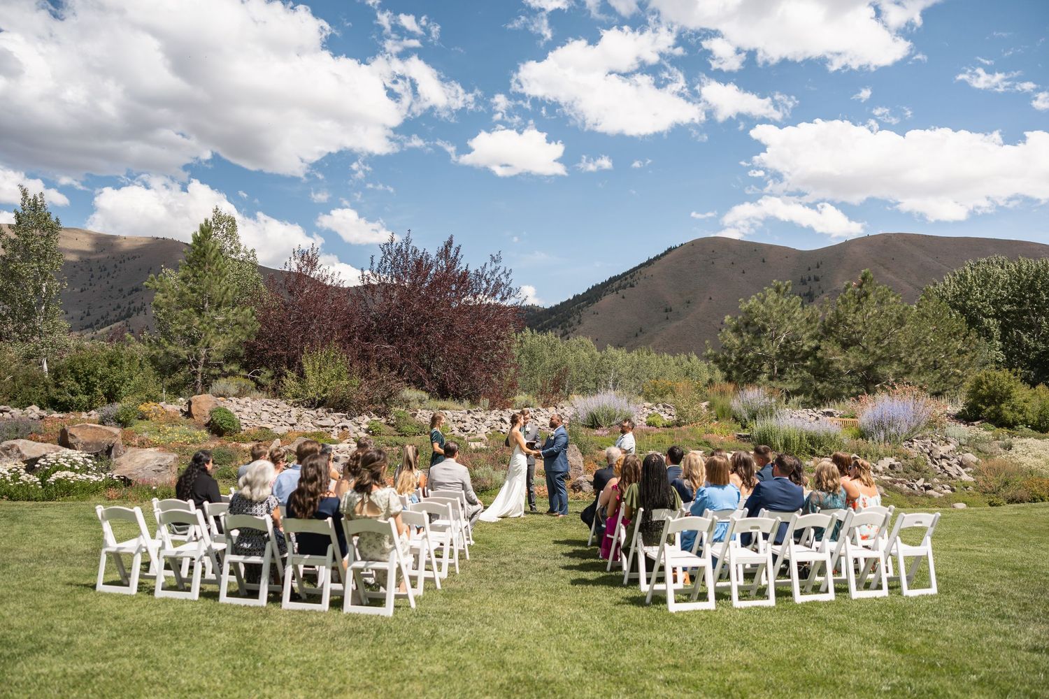 White chairs arranged for an outdoor wedding ceremony with mountain views and blue skies.