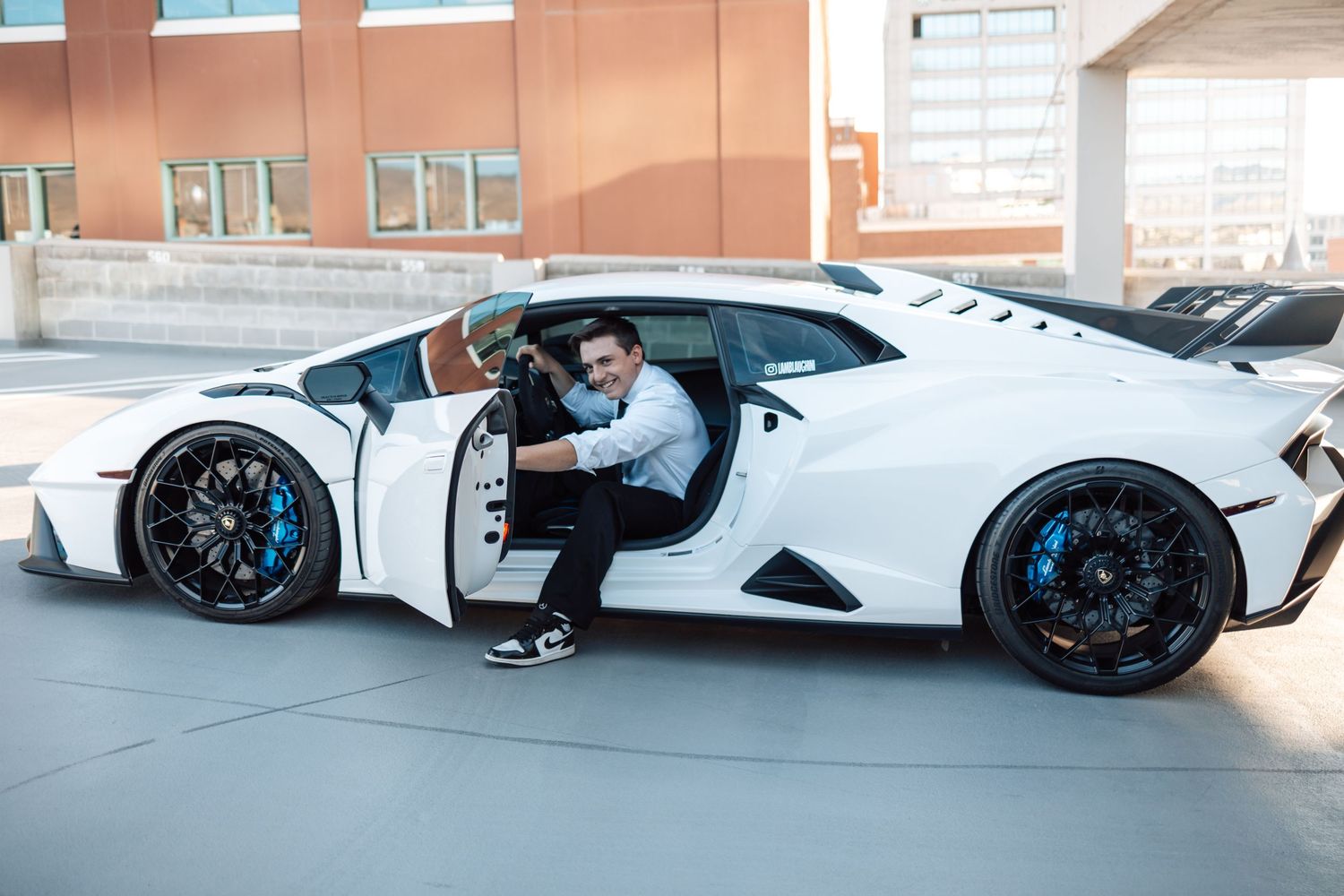 A white BMW i8 sports car with blue accents and butterfly doors parked in an indoor parking garage.