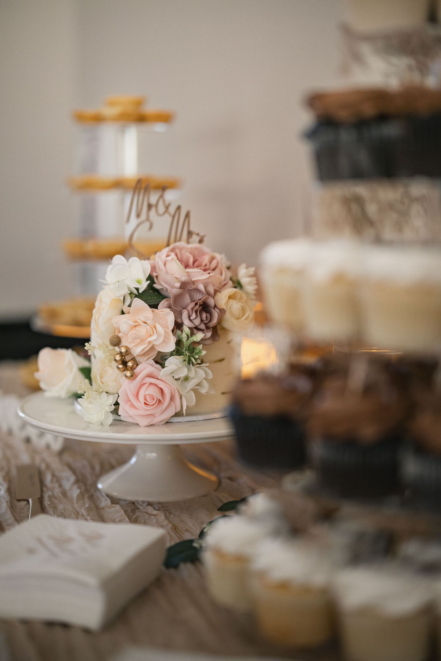 Wedding dessert display featuring tiered cakes decorated with pink and cream roses.