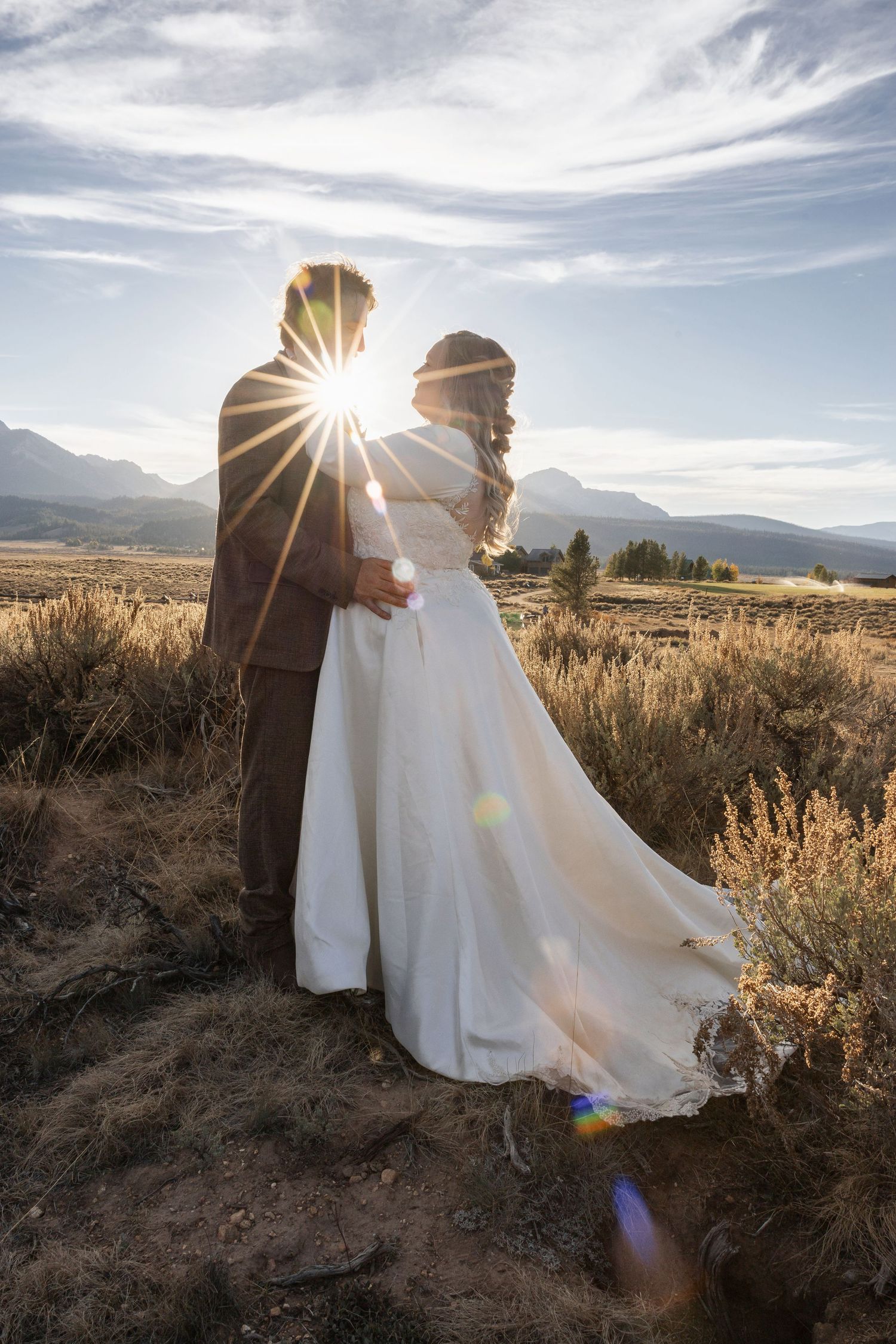 A flowing white wedding dress catches sunlight in a desert landscape with mountains in the background.