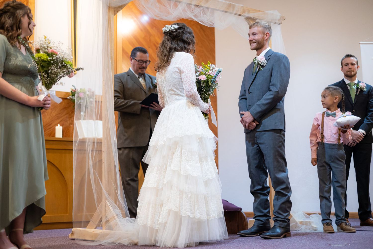 Wedding ceremony taking place in a church sanctuary with floral decorations.