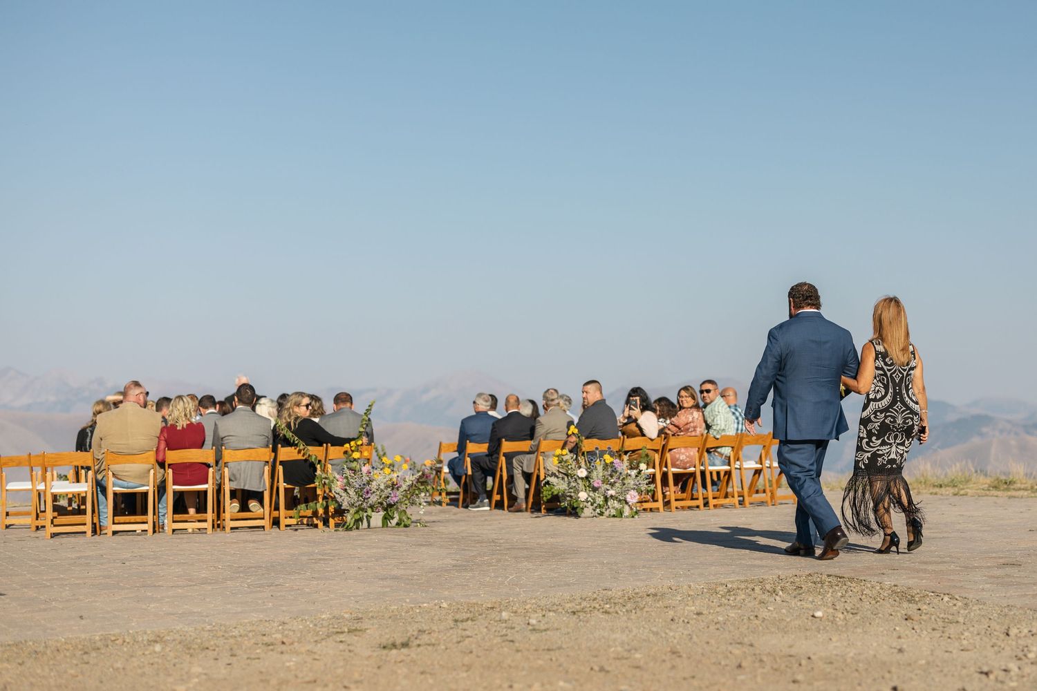Wedding ceremony setup with wooden chairs overlooking desert landscape.