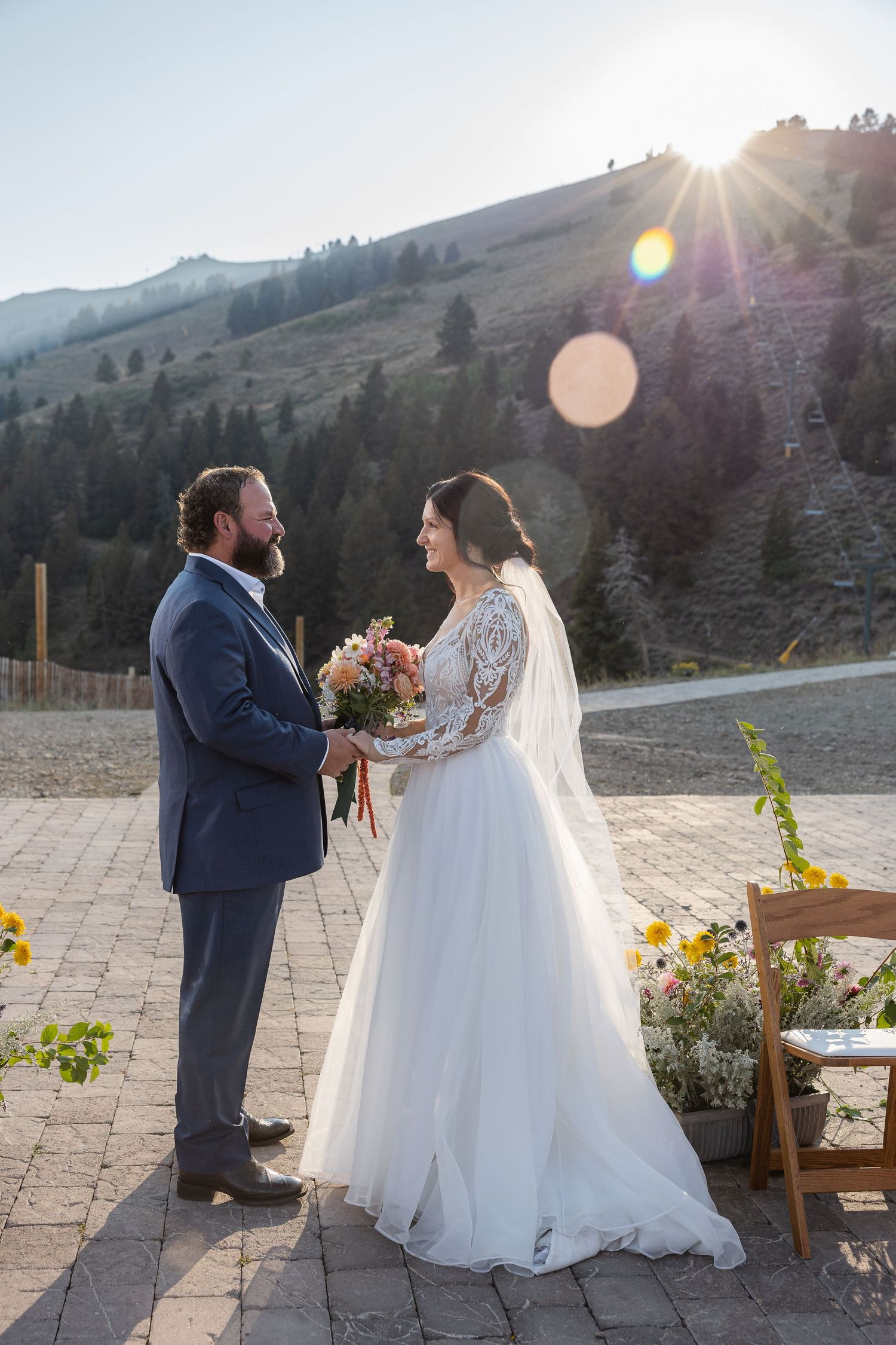 Newlyweds share a tender moment at sunset with mountain landscape in the background.