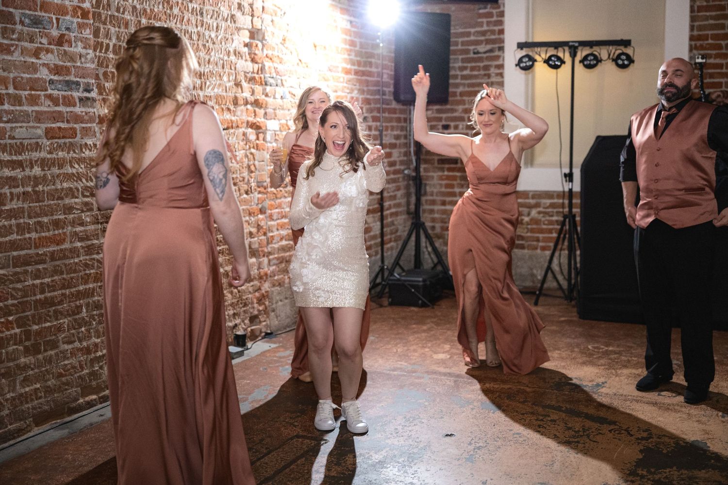 Wedding celebration in a rustic brick-walled venue with warm lighting and festive atmosphere.
